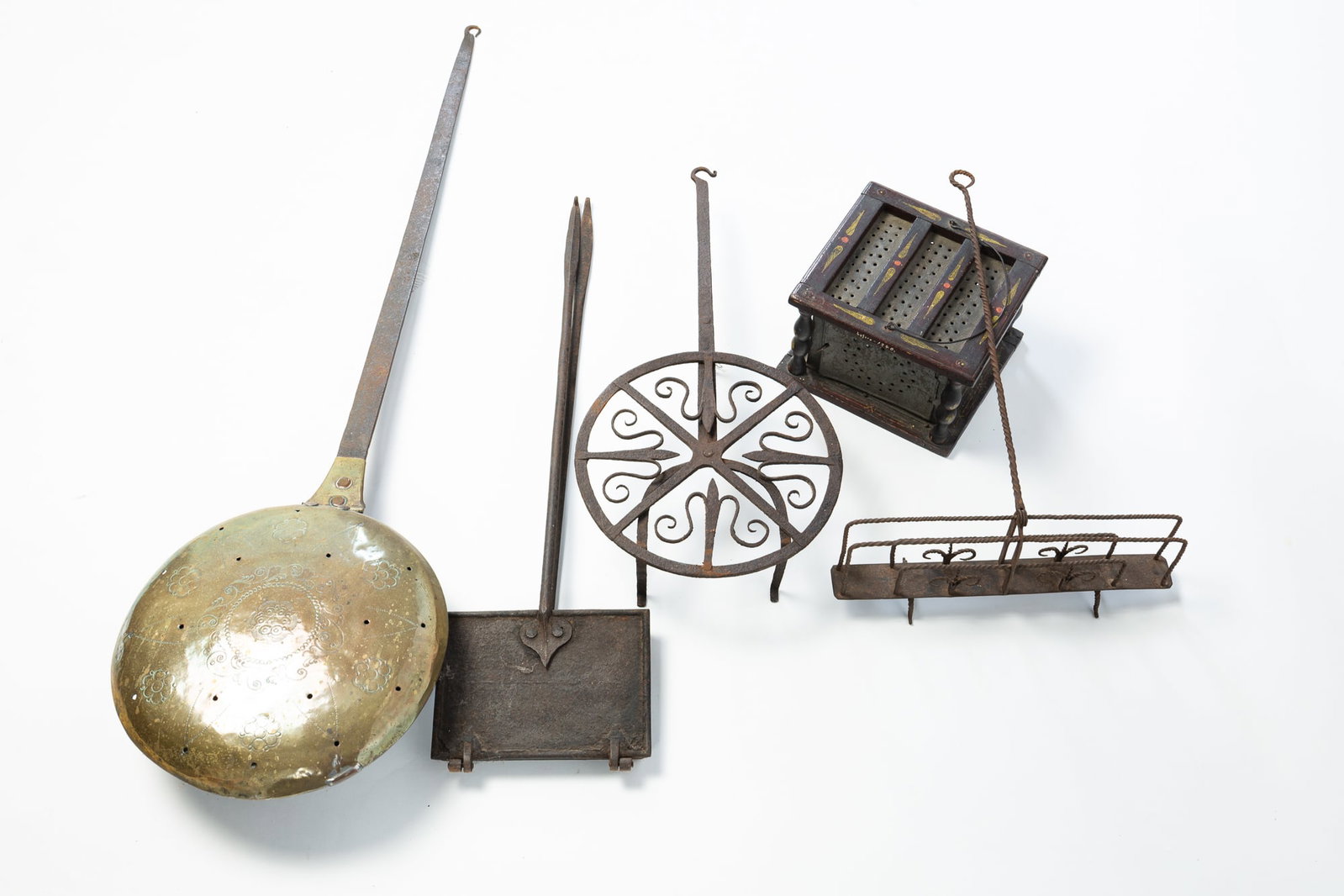 GROUP OF FIVE HEARTH ACCESSORIES.: GROUP OF FIVE HEARTH ACCESSORIES. American, 19th Century. Iron, brass, and tin. Comprising a punched tin and wood foot warmer with painted accents, a brass bed warmer with wrought iron handle, a circu