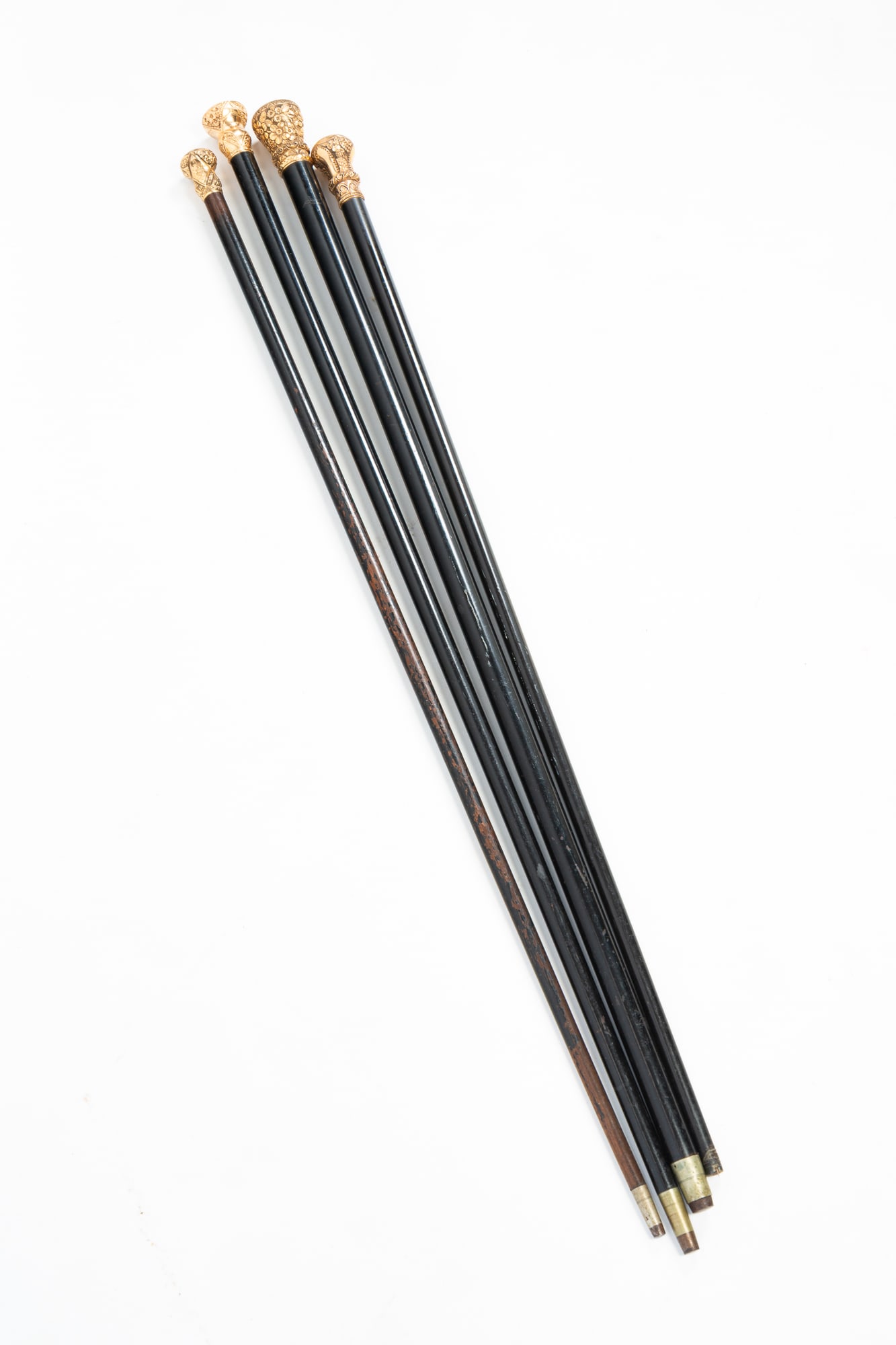 FOUR WALKING STICKS WITH GOLD-FILLED TOPS.: FOUR WALKING STICKS WITH GOLD-FILLED TOPS. American, 19th Century. Malacca. Four tapered sticks with ornate gold-filled knob handles. Some with engravings. From 36.5"h. to 32.5"h. Provenance: From the