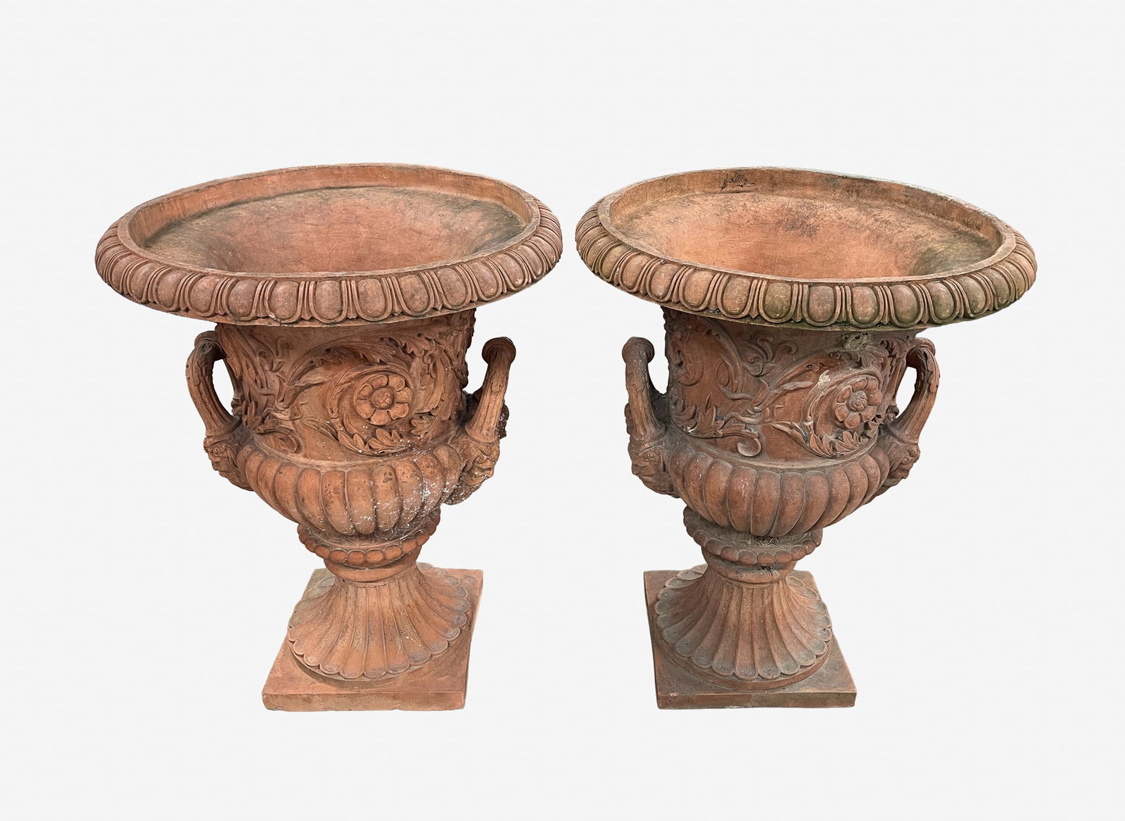 PAIR OF NEOCLASSICAL STYLE TERRACOTTA GARDEN URNS.: PAIR OF NEOCLASSICAL STYLE TERRACOTTA GARDEN URNS. Each having a flared rim above a foliate-molded body with rosettes; flanked by handles with figural mask terminals and rising on a plinth base, 30.5"