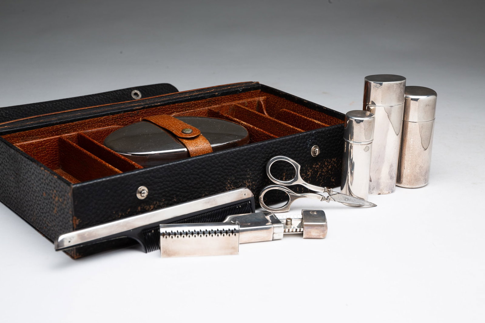 STERLING SILVER MEN'S TOILETRY KIT.: STERLING SILVER MEN'S TOILETRY KIT. American, 20th Century. Sterling silver. Leather box housing a set of men's toiletry items. Includes a brush, a comb, a collapsible shoehorn, scissors, two