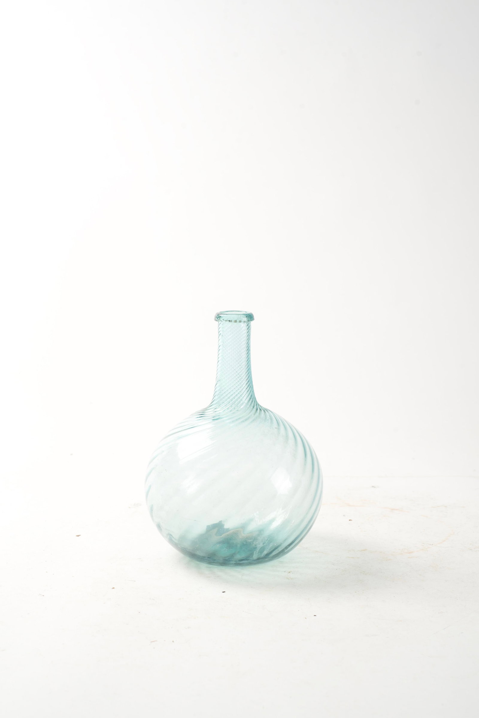 ZANESVILLE SWIRL AQUA GLASS BOTTLE.: ZANESVILLE SWIRL AQUA GLASS BOTTLE. American, first half 19th Century. Folded lip, twenty-four ribs, broken pontil, some surface wear, small pot stones, and interior residue. 7.5"h.