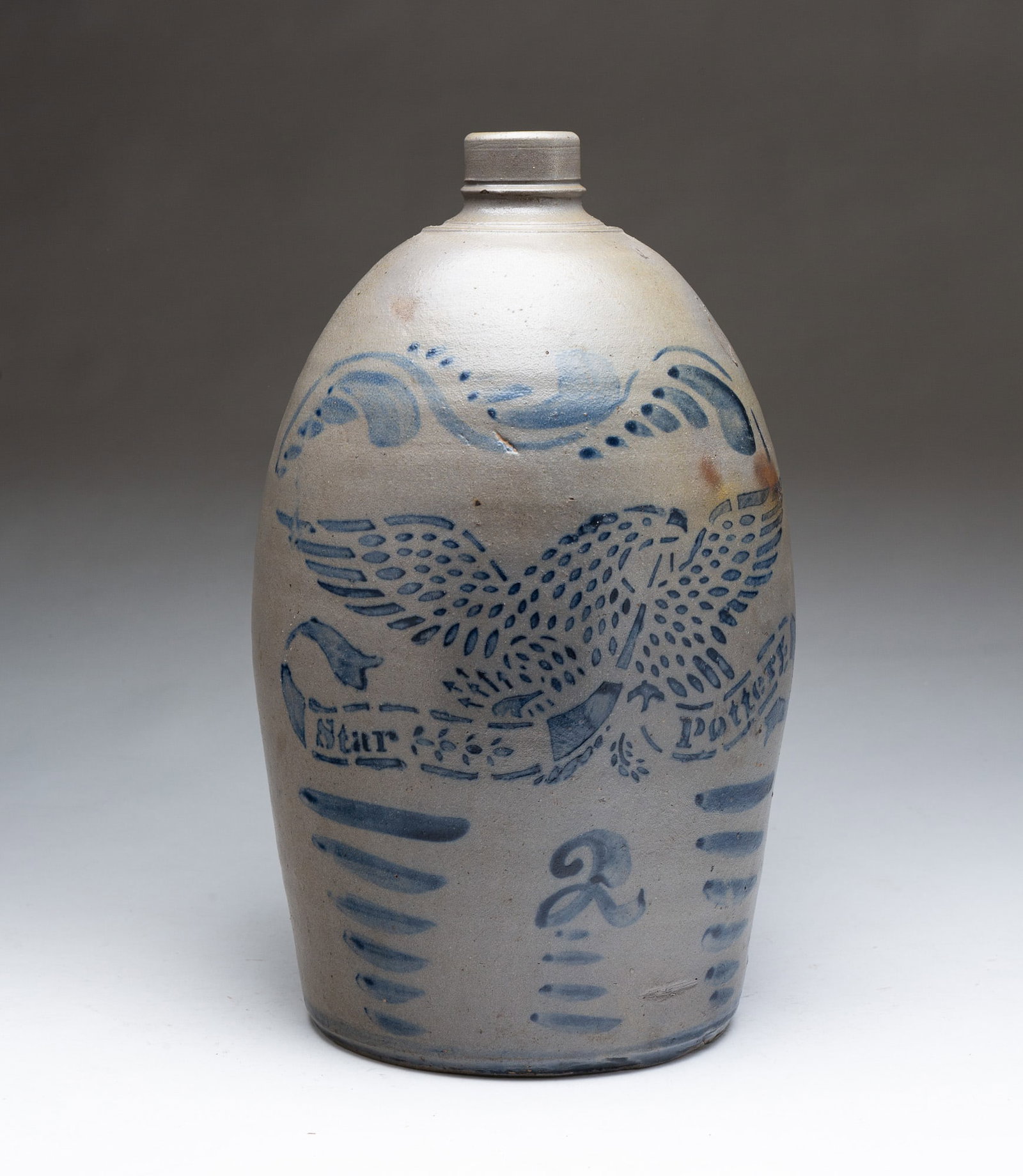 STAR POTTERY (GREENSBORO, PENNSYLVANIA) TWO GALLON STONEWARE JUG WITH STENCILED COBALT EAGLE.: STAR POTTERY (GREENSBORO, PENNSYLVANIA) TWO GALLON STONEWARE JUG WITH STENCILED COBALT EAGLE. American (Southwestern Pennsylvania), 19th Century. Slightly ovoid form with straight rim with tooling at