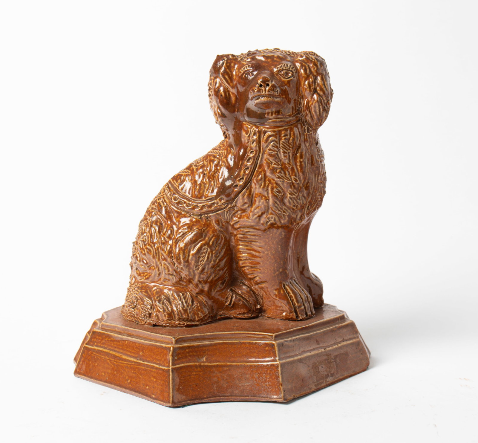ATWATER, OHIO BUFF CLAY SEATED SPANIEL IN BUTTERSCOTCH GLAZE.: ATWATER, OHIO BUFF CLAY SEATED SPANIEL IN BUTTERSCOTCH GLAZE. American, 19th Century. Seated spaniel with incised face, textured body, on a diamond base with clipped corners. 9"h. 8"w. Provenance: Nan