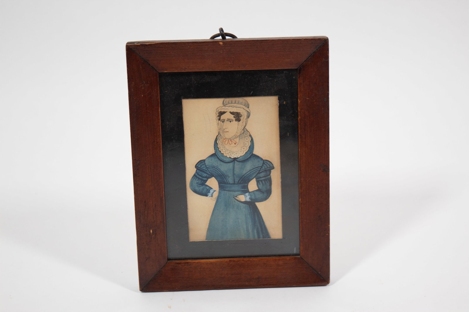 PAIR OF FRAMED WATERCOLOR HUSBAND AND WIFE PORTRAITS.: PAIR OF FRAMED WATERCOLOR HUSBAND AND WIFE PORTRAITS. American, 19th Century. Three-quarter length portraits of a husband and wife. He wears a navy blue coat with brass buttons and holds an open book.