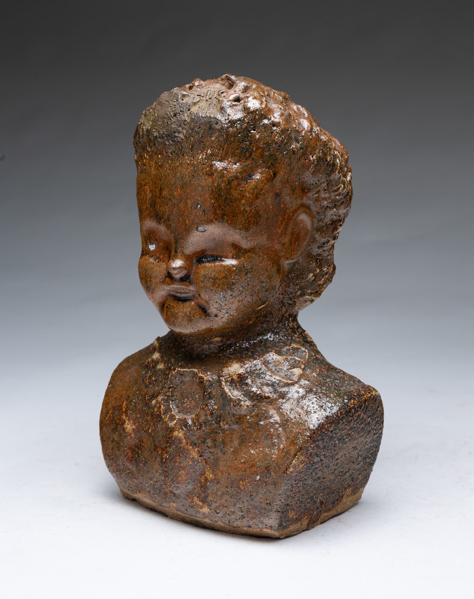 OHIO BUFF CLAY BUST OF A WOMAN.: OHIO BUFF CLAY BUST OF A WOMAN. American, 19th Century. Molded bust of a woman with curly hair and full cheeks wearing a ruffled collar, in an allover mottle brown glaze. 9.5"h.