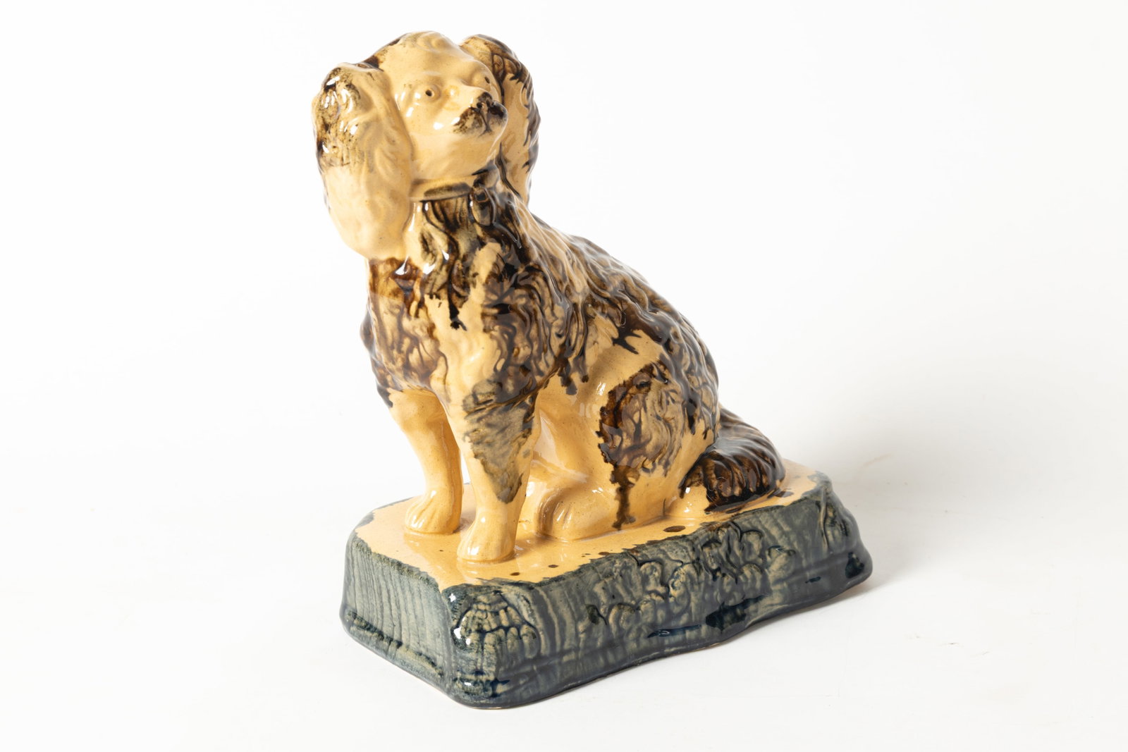 OHIO YELLOWWARE SEATED SPANIEL.: OHIO YELLOWWARE SEATED SPANIEL. American (possibly East Liverpool), 19th Century. Seated spaniel with free-standing front legs, seated on a shaped plinth with clipped corners and a mottled brown and b