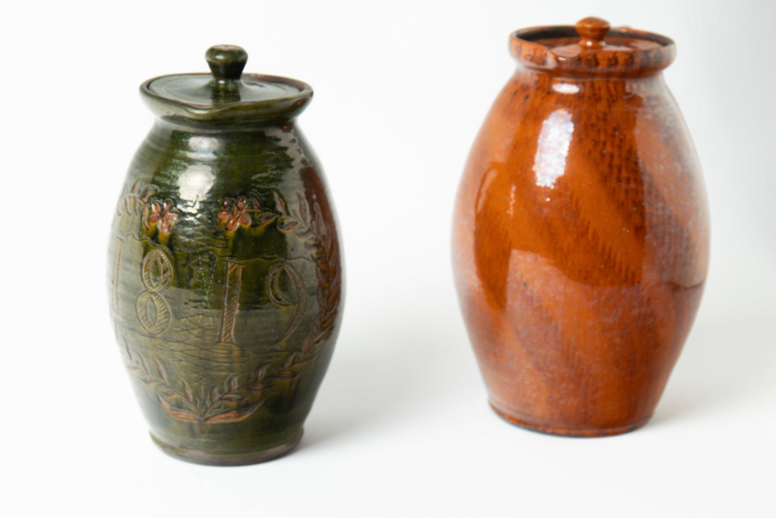 TWO GREG SHOONER (OREGONIA, OHIO, B. 1953) GLAZED REDWARE POTTERY LIDDED PITCHERS. (1 of 13)