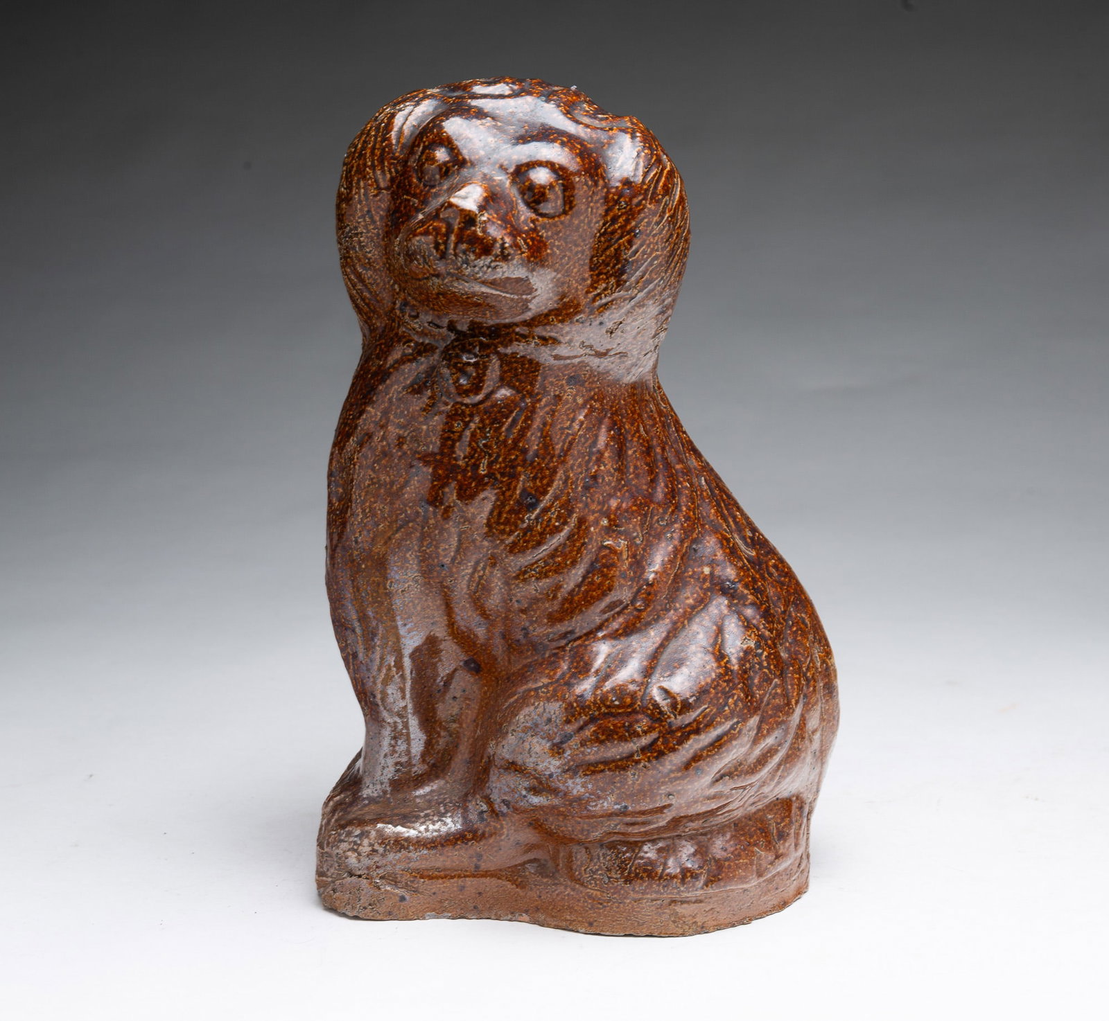 OHIO SEWER TILE SEATED SPANIEL.: OHIO SEWER TILE SEATED SPANIEL. American, late 19th Century. Seated spaniel wearing a collar, with molded and incised decoration, and allover mottled brown glaze. 10.5"h.