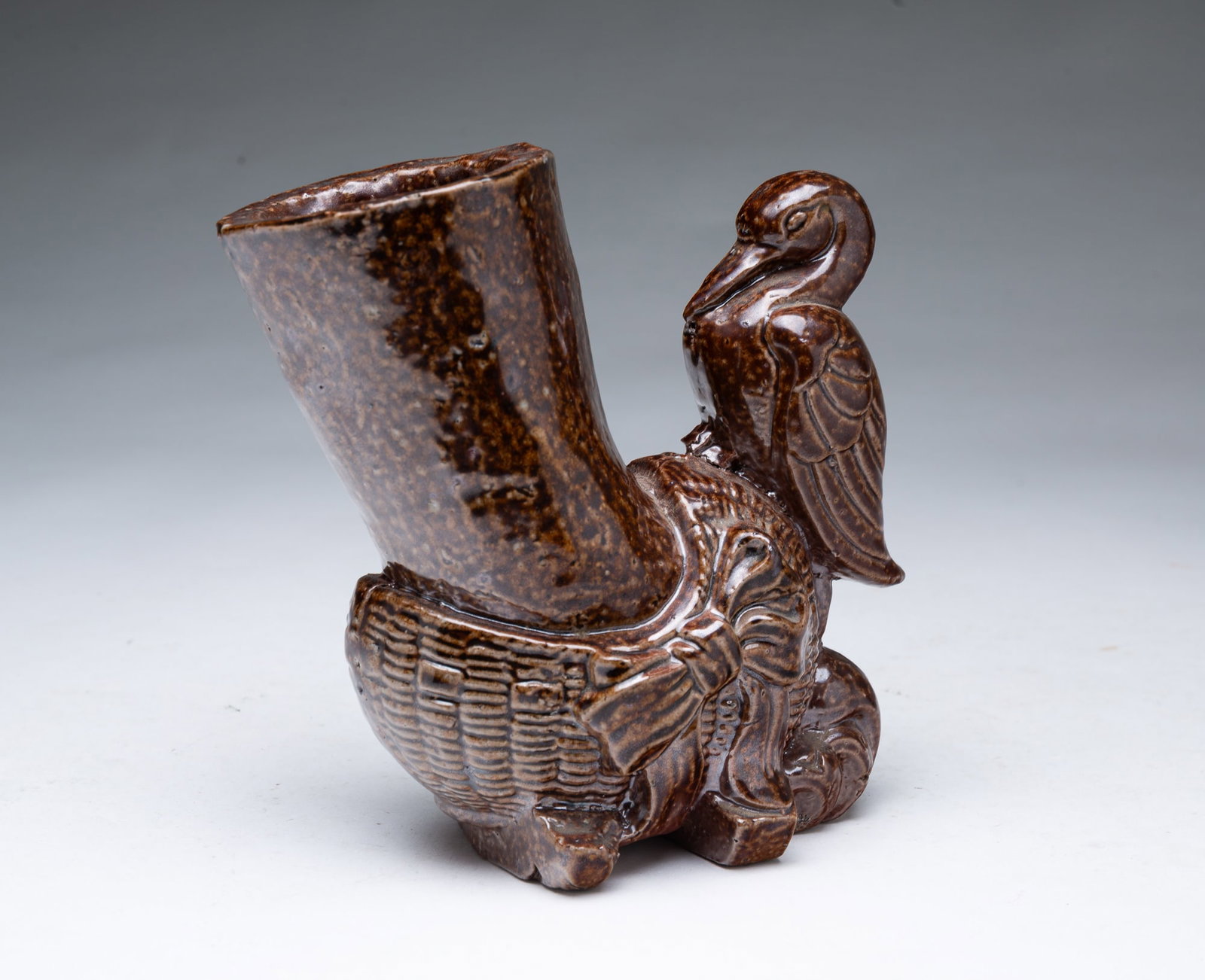 OHIO SEWER TILE VASE WITH CRADLE AND STORK.: OHIO SEWER TILE VASE WITH CRADLE AND STORK. American, 19th Century. Molded cylindrical vase set at an angle in a wicker cradle with a stork perched on it. 6.5"h.