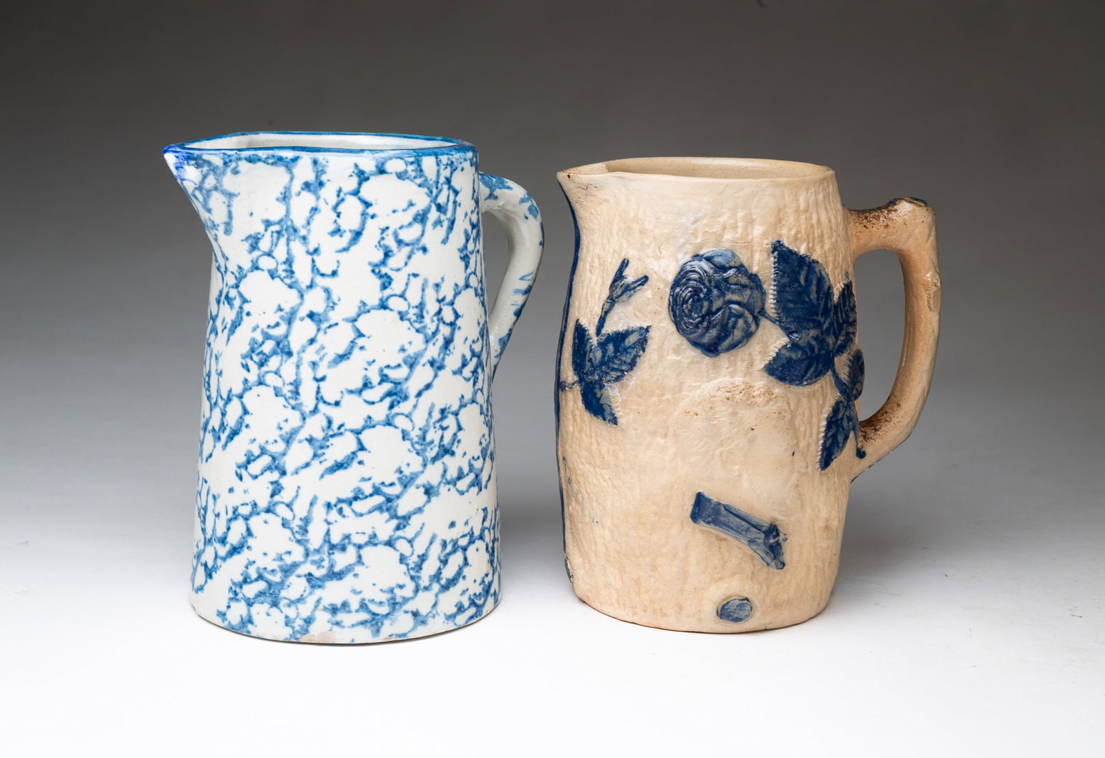 TWO STONEWARE MILK PITCHERS.: TWO STONEWARE MILK PITCHERS. American, late 19th or early 20th Century. A canted side pitcher with blue sponged decoration, 8.75"h., a White's Utica General Sherman and Lady Liberty pitcher with cobal