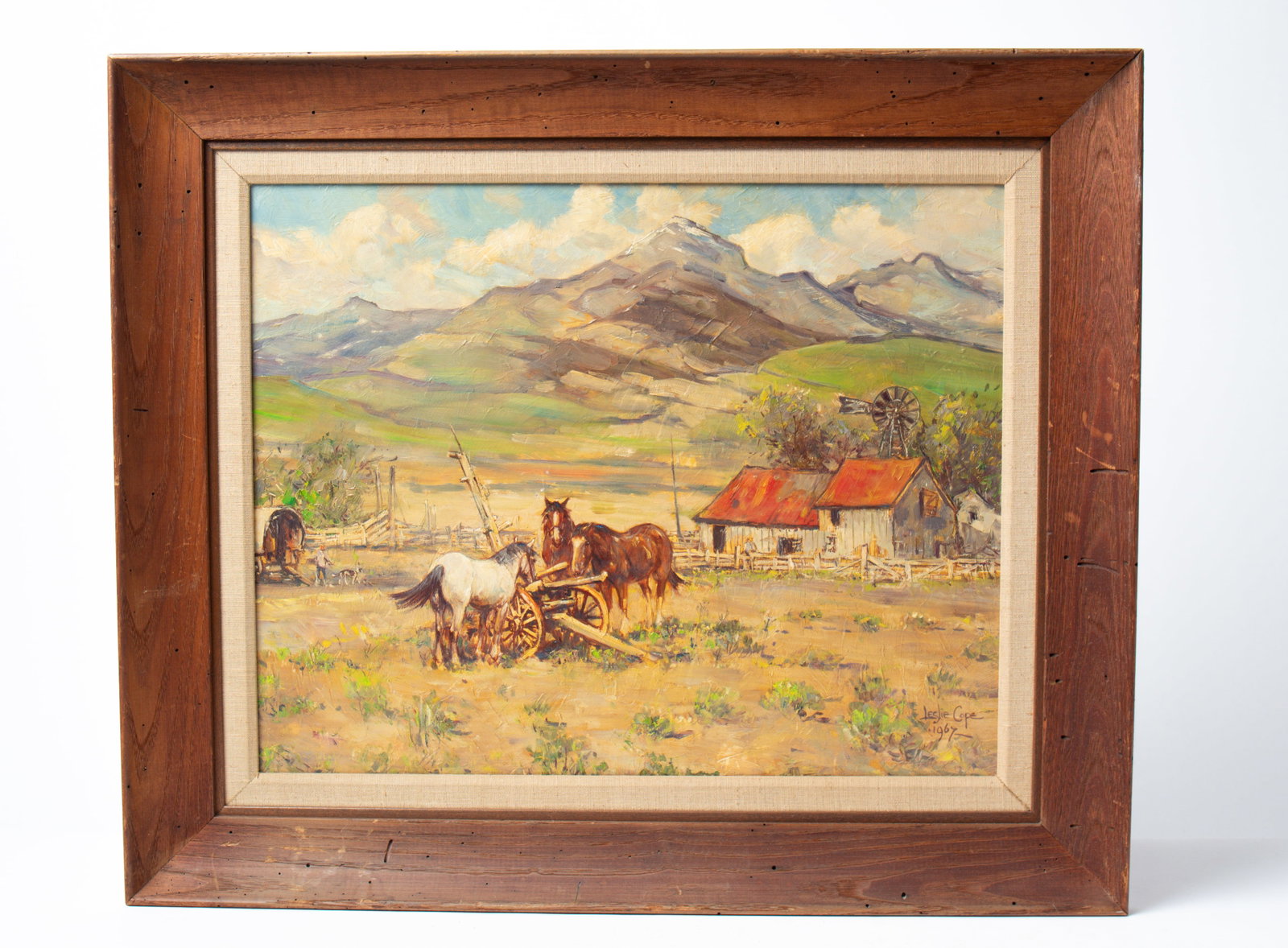LESLIE COPE (OHIO, 1913 - 2002) "A NEVADA LANDSCAPE" OIL ON BOARD.: LESLIE COPE (OHIO, 1913 - 2002) "A NEVADA LANDSCAPE" OIL ON BOARD. American (Mt. Hope, Ohio), Dated 1967. Depicting a farm scene with three horses by a plow, a man and dog with covered wagon, and a ba