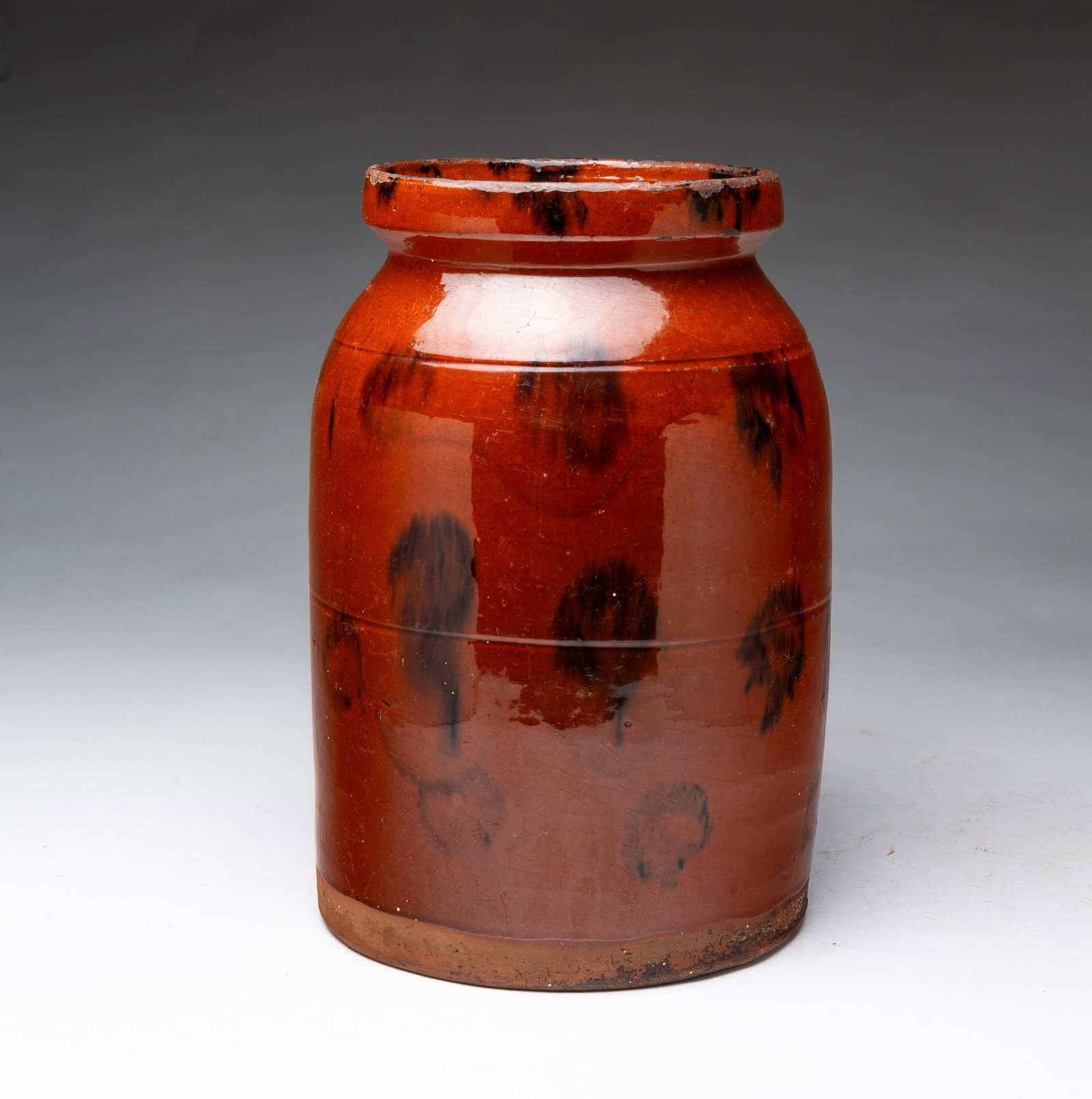 LARGE GLAZED REDWARE JAR WITH MANGANESE DECORATION.: LARGE GLAZED REDWARE JAR WITH MANGANESE DECORATION. American, 19th Century. Tall jar with pronounced top lip, tooled shoulder and waist, having an allover dark orange glaze stopping short of the foot,