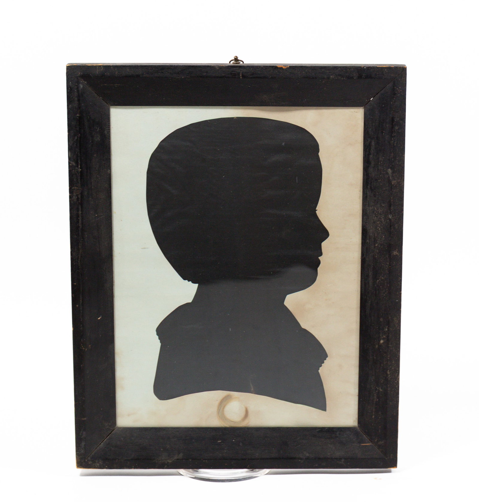 LIFE-SIZE HOLLOW CUT SILHOUETTE OF A YOUNG BOY.: LIFE-SIZE HOLLOW CUT SILHOUETTE OF A YOUNG BOY. American, early 19th Century. Cut paper. A boy seated facing left, and wearing a collared shirt. A lock of his blonde hair is framed beneath the silhoue