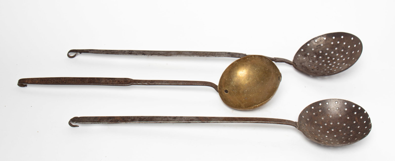 TWO STAMPED FORGED IRON SKIMMERS AND A STAMPED IRON AND BRASS LADLE. (1 of 5)