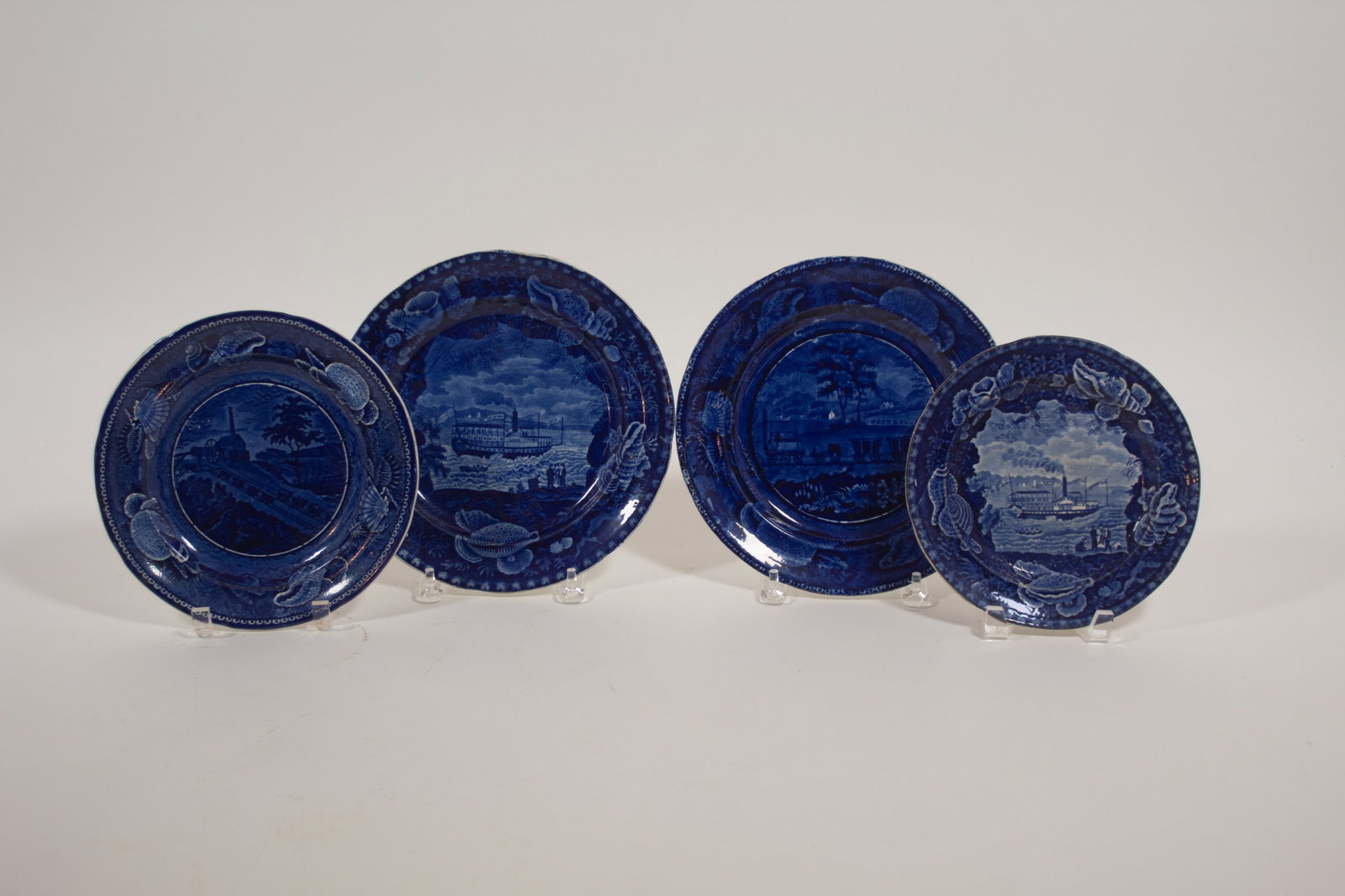 FOUR ENOCH WOOD AND SONS HISTORICAL BLUE PLATES WITH AMERICAN TRANSPORTATION SCENES.: FOUR ENOCH WOOD AND SONS HISTORICAL BLUE PLATES WITH AMERICAN TRANSPORTATION SCENES. England, mid- 19th Century. All four with shell borders and impressed marks. Sidewheel steamboat "CHIEF JUSTICE MAR