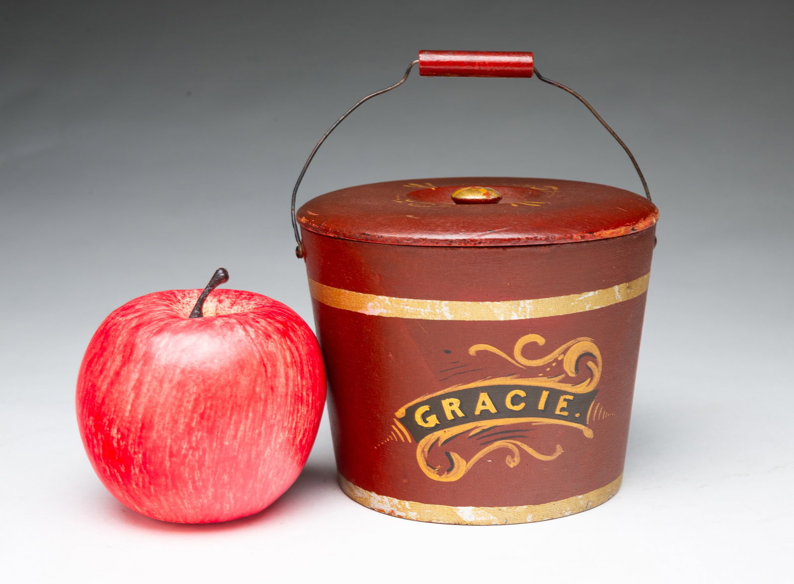 MINIATURE E. MURDOCK & CO. (WINCHENDON, MASSACHUSETTS) LIDDED BERRY BUCKET IN ORIGINAL RED WITH: MINIATURE E. MURDOCK & CO. (WINCHENDON, MASSACHUSETTS) LIDDED BERRY BUCKET IN ORIGINAL RED WITH CARRIAGE PAINT DECORATION. American, 19th Century. Turned wood. Lid with gilt decoration and finial, hav