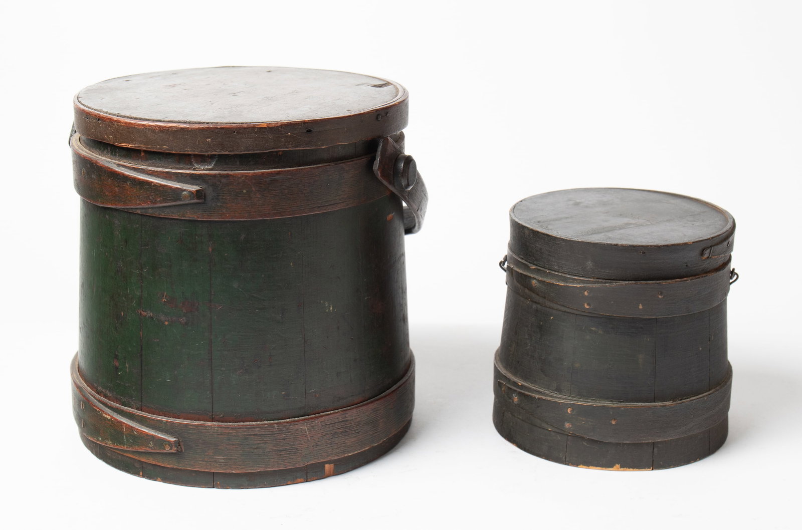 TWO FIRKINS WITH ORIGINAL PAINT.: TWO FIRKINS WITH ORIGINAL PAINT. American, 19th Century. Pine. The first of stave construction, having lapped bands with copper tacks and a bentwood swing handle. In nice worn green paint. With handle