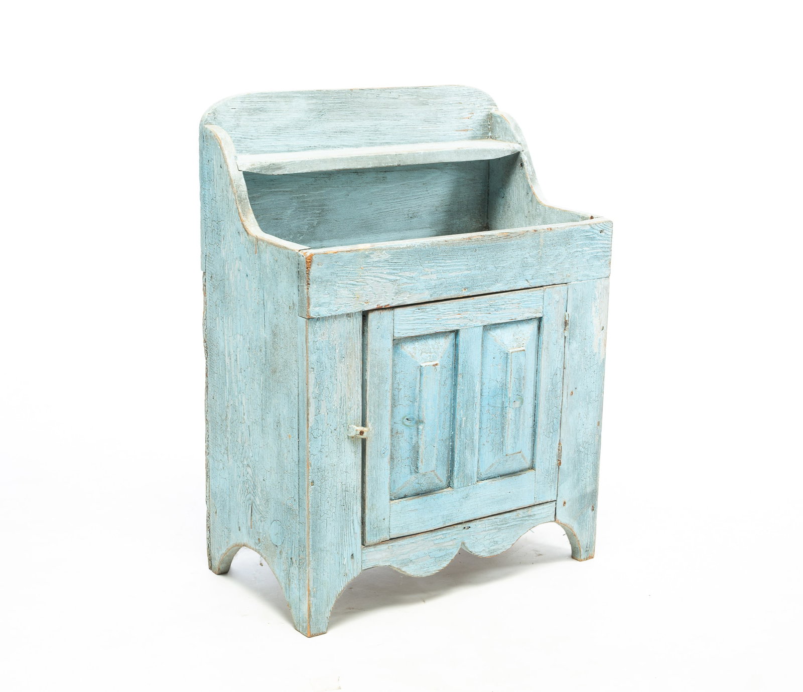 DIMINUTIVE BLUE-PAINTED CHILD'S HIGH-BACK DRY SINK.: DIMINUTIVE BLUE-PAINTED CHILD'S HIGH-BACK DRY SINK. American, 20th Century. Oak. Back with shelf, deep well, half-round cut-out ends, double-raised panel door, and shaped apron. Layered blue paint. As