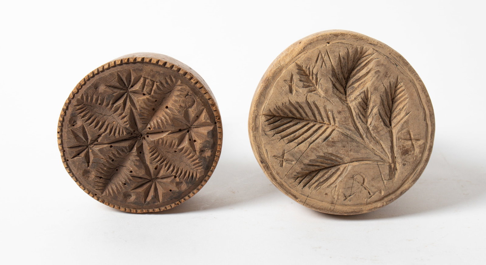 TWO LARGE CARVED WOODEN BUTTER PRINTS.: TWO LARGE CARVED WOODEN BUTTER PRINTS. American, 19th Century. The first of circular form, having a chip-carved edge, central leaf motif, three dots, and four pinwheels, the exterior carved with "LNL.