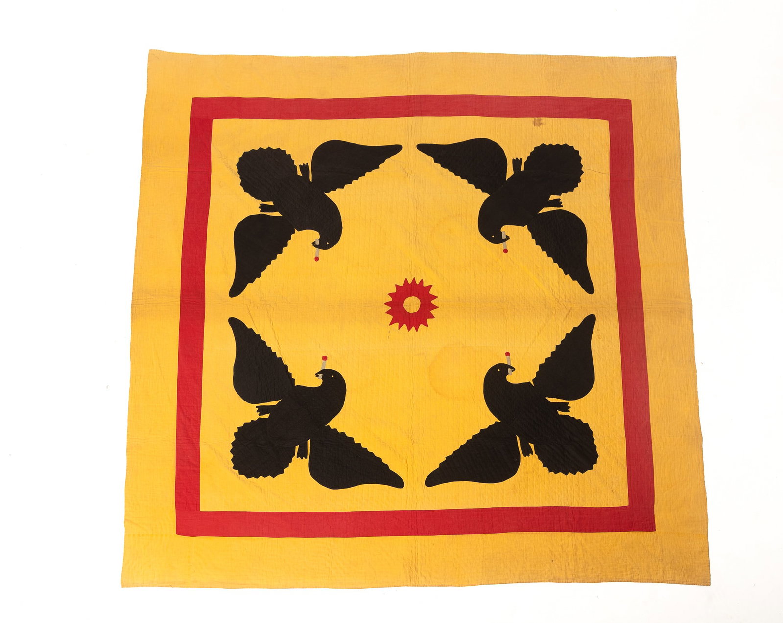 AMERICAN EAGLE APPLIQUE QUILT.: AMERICAN EAGLE APPLIQUE QUILT. American, mid- 19th Century. Hand-stitched. Yellow ground with four black eagles at the corners with a lit cigarette in its mouth, a starburst to center, and a red