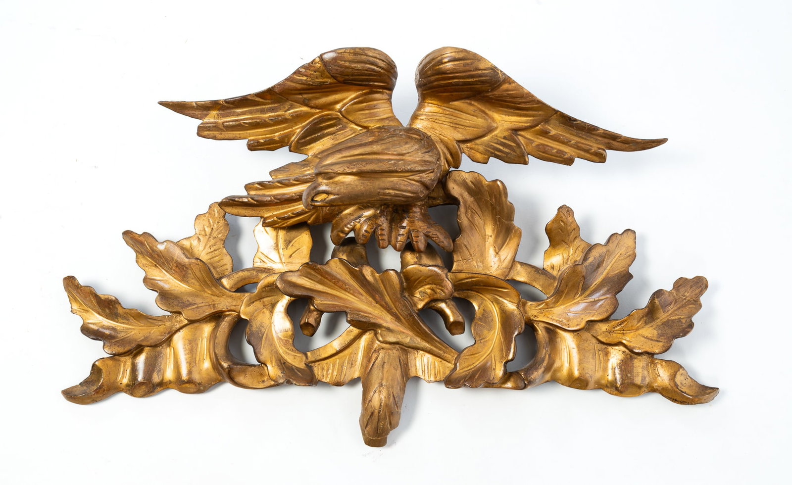 SMALL GILTWOOD SPREAD-WINGED EAGLE CARVING.: SMALL GILTWOOD SPREAD-WINGED EAGLE CARVING. American, 19th Century. Depicting a spread-winged eagle with head turned to the left perched on a leafy branch. Provenance: From the Lifetime Collection of