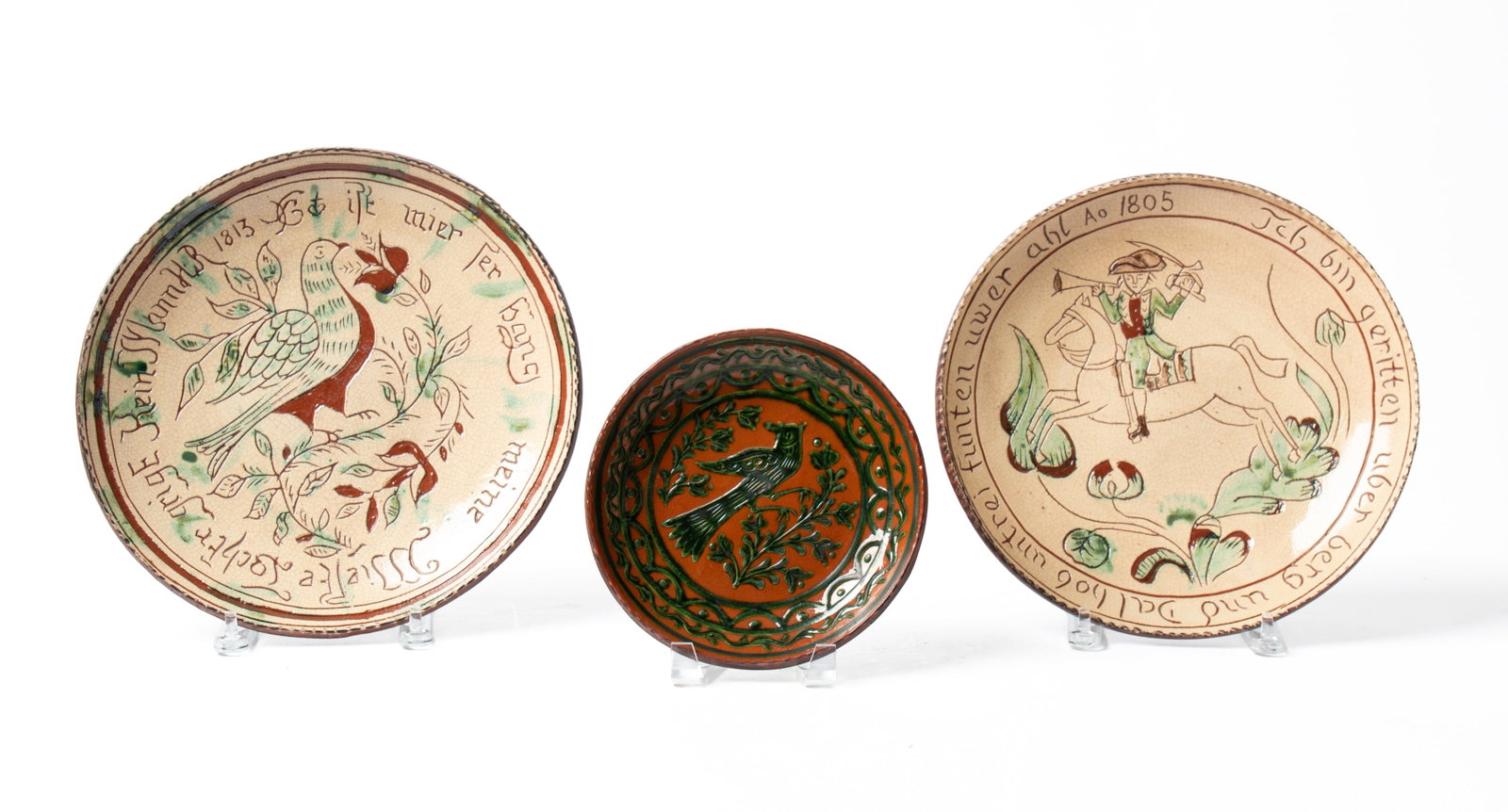 THREE TURTLE CREEK REDWARE PLATES.: THREE TURTLE CREEK REDWARE PLATES. American (Ohio), contemporary. One with high glaze, green slip decoration, central bird and vining and scalloped border, 7.5"d., a colonial gentleman on horseback,