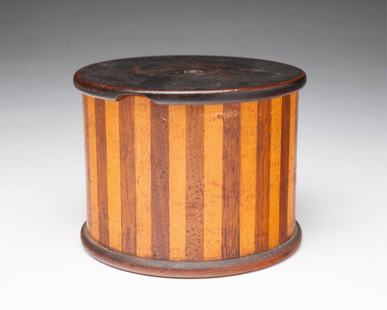 SHAKER TREENWARE STRING HOLDER.: SHAKER TREENWARE STRING HOLDER. American, 19th Century. Mixed woods. Drum-form case with slightly overhanging top and base; 3.25"h. 4.25"d. Provenance: Nancy Goff (Alliance, Ohio).