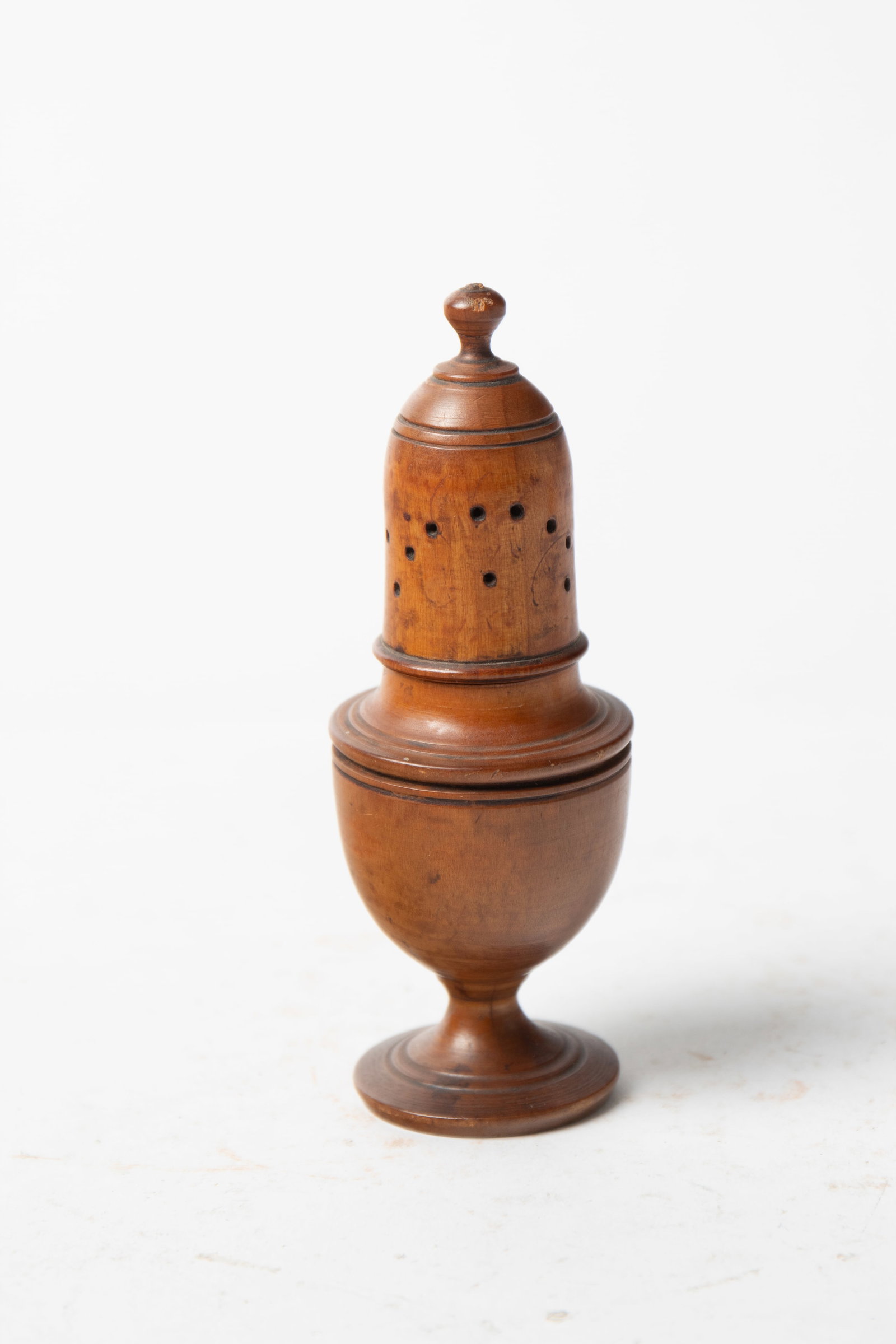 TREEN PEPPER POT.: TREEN PEPPER POT. American, 19th Century. Having a turned finial above a cylindrical, pierced body and footed base; 5.5"h. 2"w. Provenance: Nancy Goff (Alliance, Ohio).
