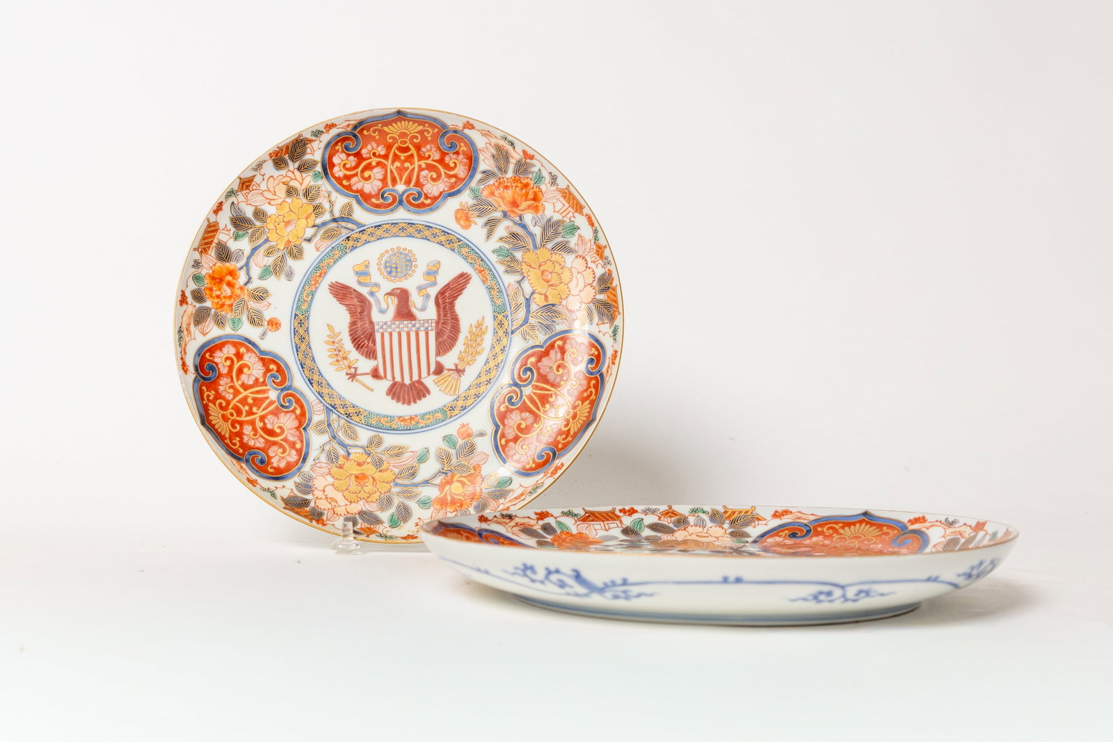 TWO HAND PAINTED JAPANESE IMARI PLATES WITH THE SEAL OF THE UNITED STATES FROM THE AMBASSADOR GEORGE: TWO HAND PAINTED JAPANESE IMARI PLATES WITH THE SEAL OF THE UNITED STATES FROM THE AMBASSADOR GEORGE W. GUTHRIE SERVICE. First quarter 20th Century. Floral border, spread winged eagle at center with