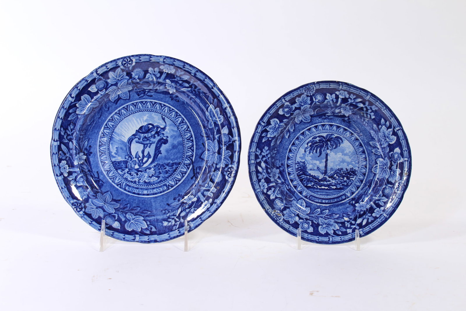 TWO STAFFORDSHIRE HISTORICAL BLUE STATE SEAL PLATES.: TWO STAFFORDSHIRE HISTORICAL BLUE STATE SEAL PLATES. England, mid- 19th Century. Floral borders, eagle with shield surrounded by thirteen stars and ribbon "E. PLURIBUS UNIM" transfer makersmark.