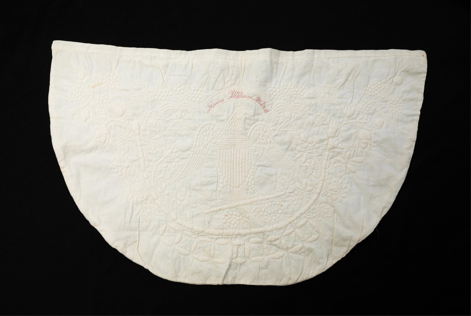 DEMILUNE STUFFED TABLE COVER BY LANNA WILLIAMS, DATED 1847.: DEMILUNE STUFFED TABLE COVER BY LANNA WILLIAMS, DATED 1847. American, mid- 19th Century. Cotton. Spread-winged American eagle with shield on chest to center surrounded by vining flowers and grapes.