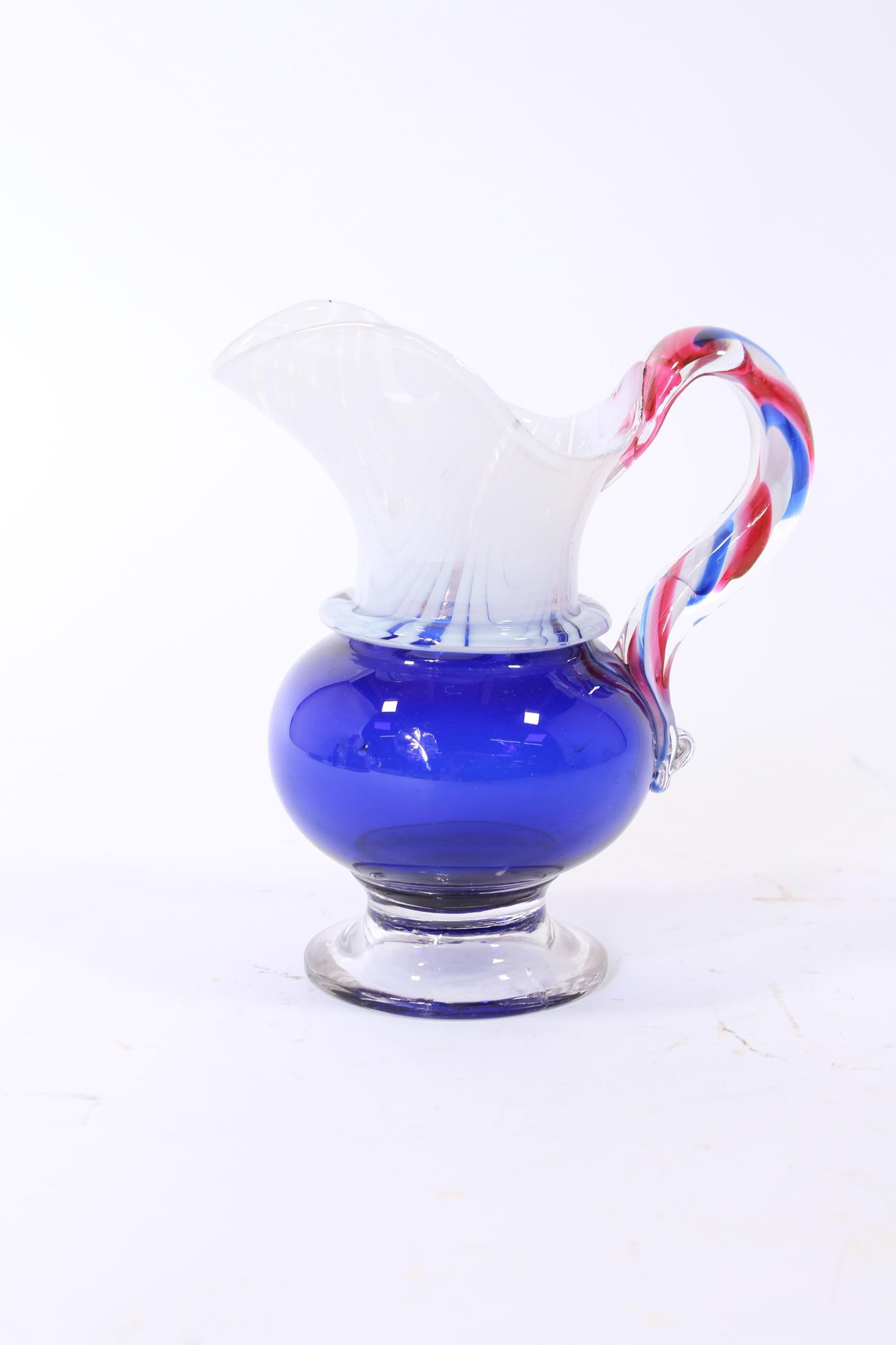 PATRIOTIC RED, WHITE, AND BLUE PITTSBURGH BLOWN GLASS PITCHER.: PATRIOTIC RED, WHITE, AND BLUE PITTSBURGH BLOWN GLASS PITCHER. American (Pennsylvania), early 19th Century. Pitcher with a cobalt over clear bowl, clear spout with white loops, clear circular foot, an