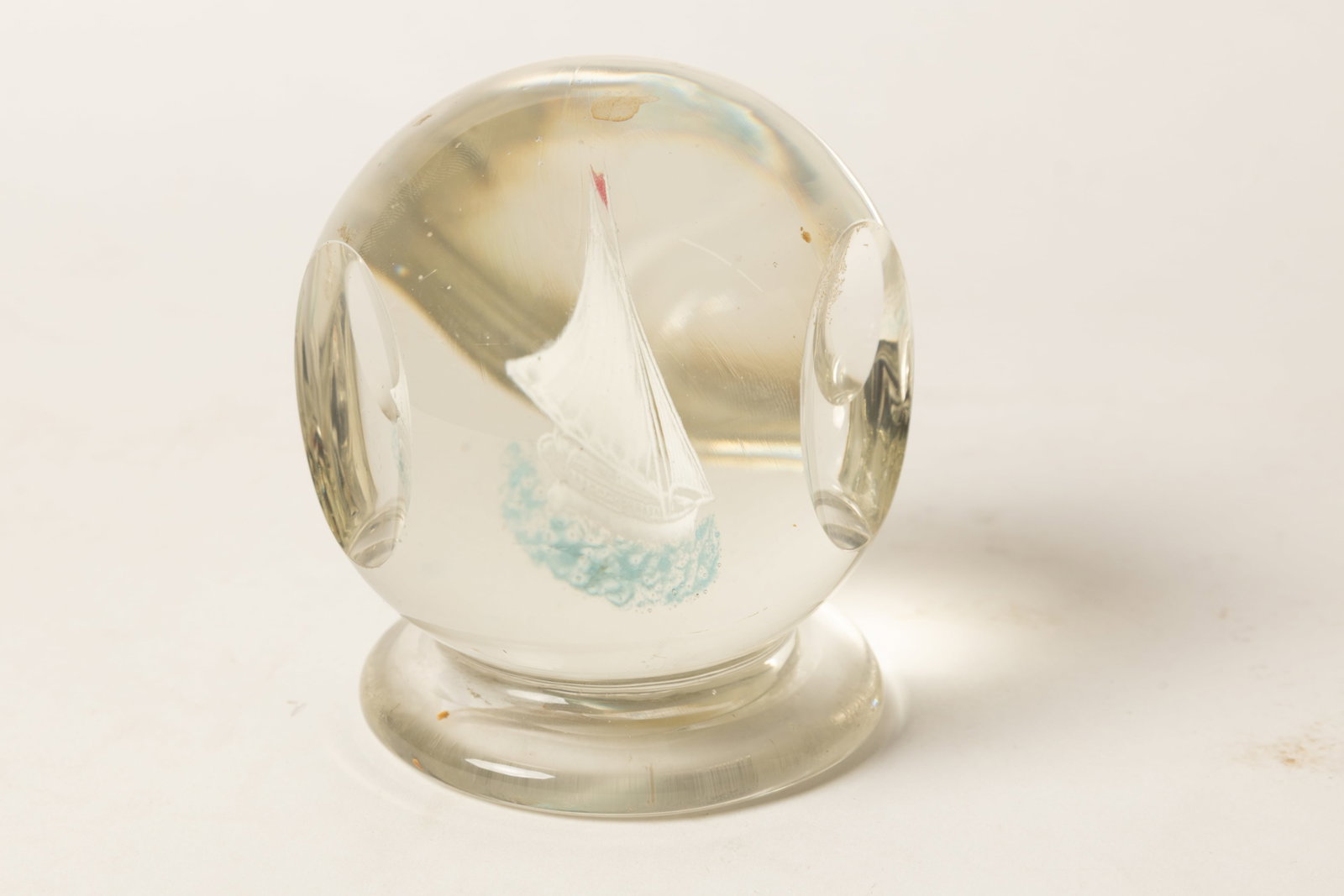 PAPERWEIGHT WITH SAILING SHIP ATTRIBUTED TO THE NEW ENGLAND GLASS COMPANY.: PAPERWEIGHT WITH SAILING SHIP ATTRIBUTED TO THE NEW ENGLAND GLASS COMPANY. American, Second half 19th Century. Spherical shape on a wafer base, three large concave dimples on sides and interior with