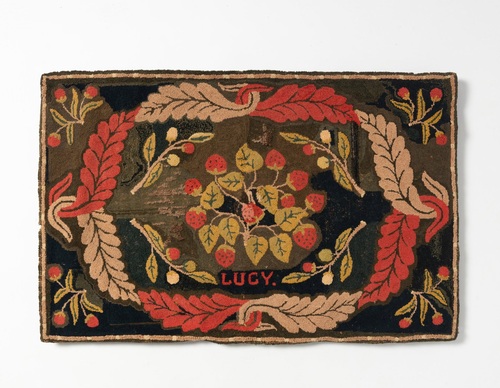WONDERFUL EARLY YARN SEWN RUG WITH STRAWBERRIES AND "LUCY".: WONDERFUL EARLY YARN SEWN RUG WITH STRAWBERRIES AND "LUCY". American, 19th century. Wool on burlap. Feathered oval wreath in alternating pale pink and red enclosing a group of well-detailed
