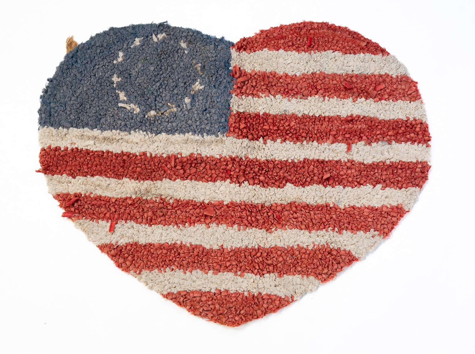 HEART SHAPED AMERICAN FLAG HOOKED RUG.: HEART SHAPED AMERICAN FLAG HOOKED RUG. Early 20th Century. Blue field with a circle of white stars and red and white stripes. 35"w. 25"h. Provenance: From the Lifetime Quilt and Textile Collection of