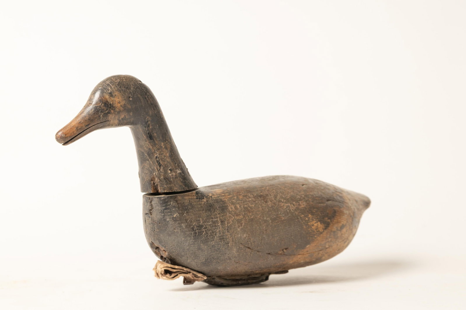 EARLY BRANT FOLK ART CARVED DUCK DECOY.: EARLY BRANT FOLK ART CARVED DUCK DECOY. Hog Island, Virginia, Late 19th Century. Traditional duck form with dark, worn paint. Canvas pull and weight to bottom. 9"h. 16"l. Cataloger's note: Hog Island 