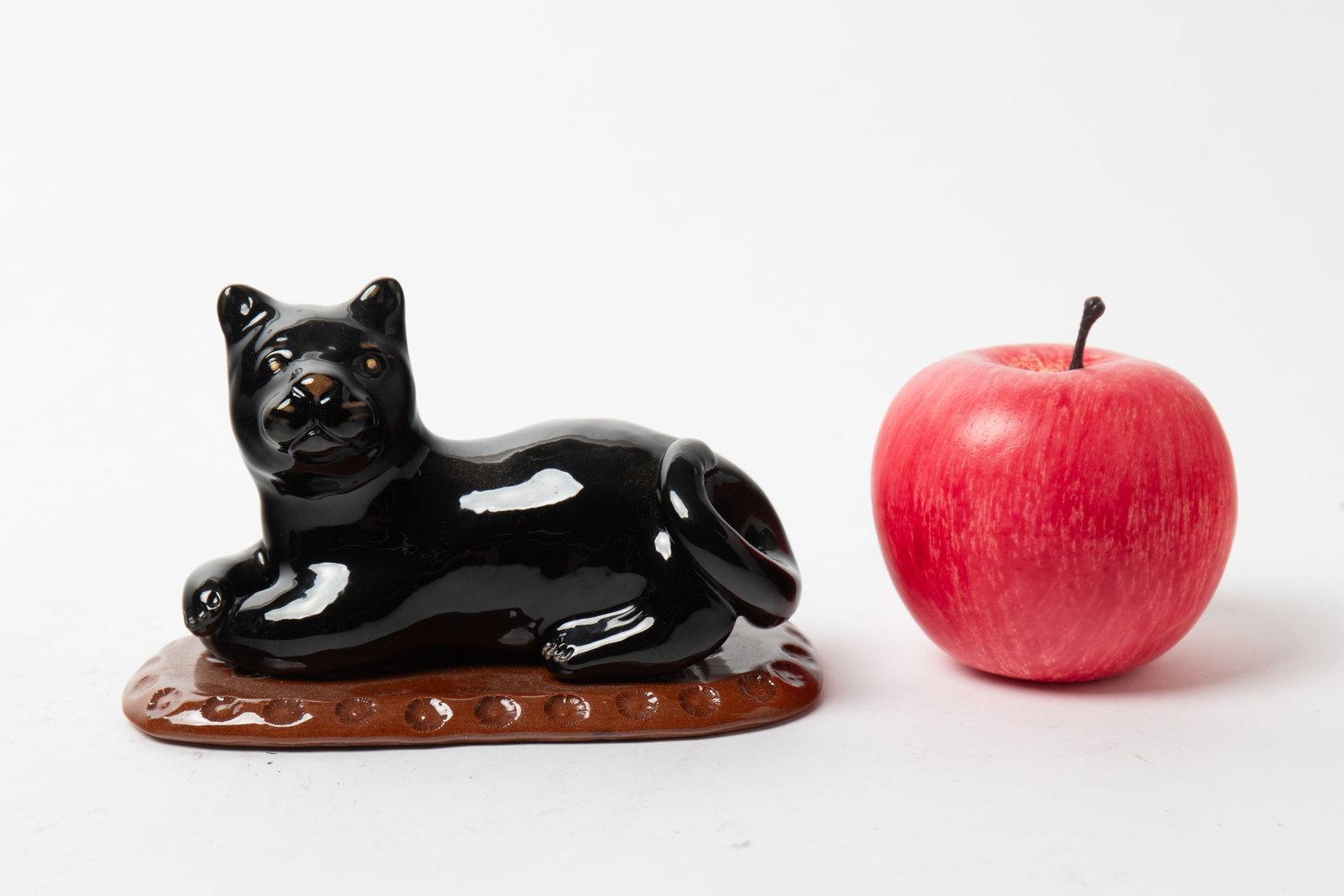 BREININGER POTTERY (ROBESONIA, PENNSYLVANIA) GLAZED REDWARE RECUMBENT CAT.: BREININGER POTTERY (ROBESONIA, PENNSYLVANIA) GLAZED REDWARE RECUMBENT CAT. American, Dated 2006. Signed and dated to bottom. A black cat lying on a red mat with impressed pattern at rim. 4"h. 6"w. Pro