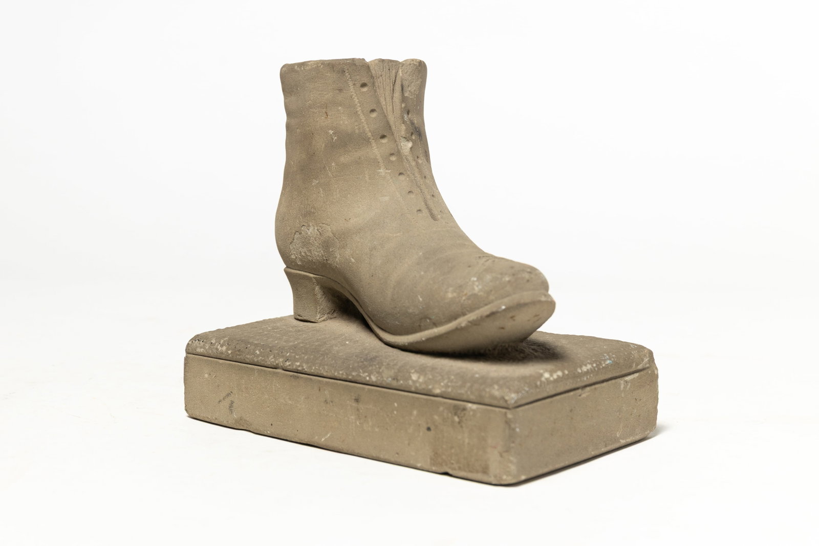 FOLKSY CARVED LIMESTONE SHOE.: FOLKSY CARVED LIMESTONE SHOE. American, 19th Century. A lace-up ankle boot with a slight heel on a rectangular plinth. 6"h. 6.4"w. 4"d. Provenance: Nancy Goff (Alliance, Ohio).
