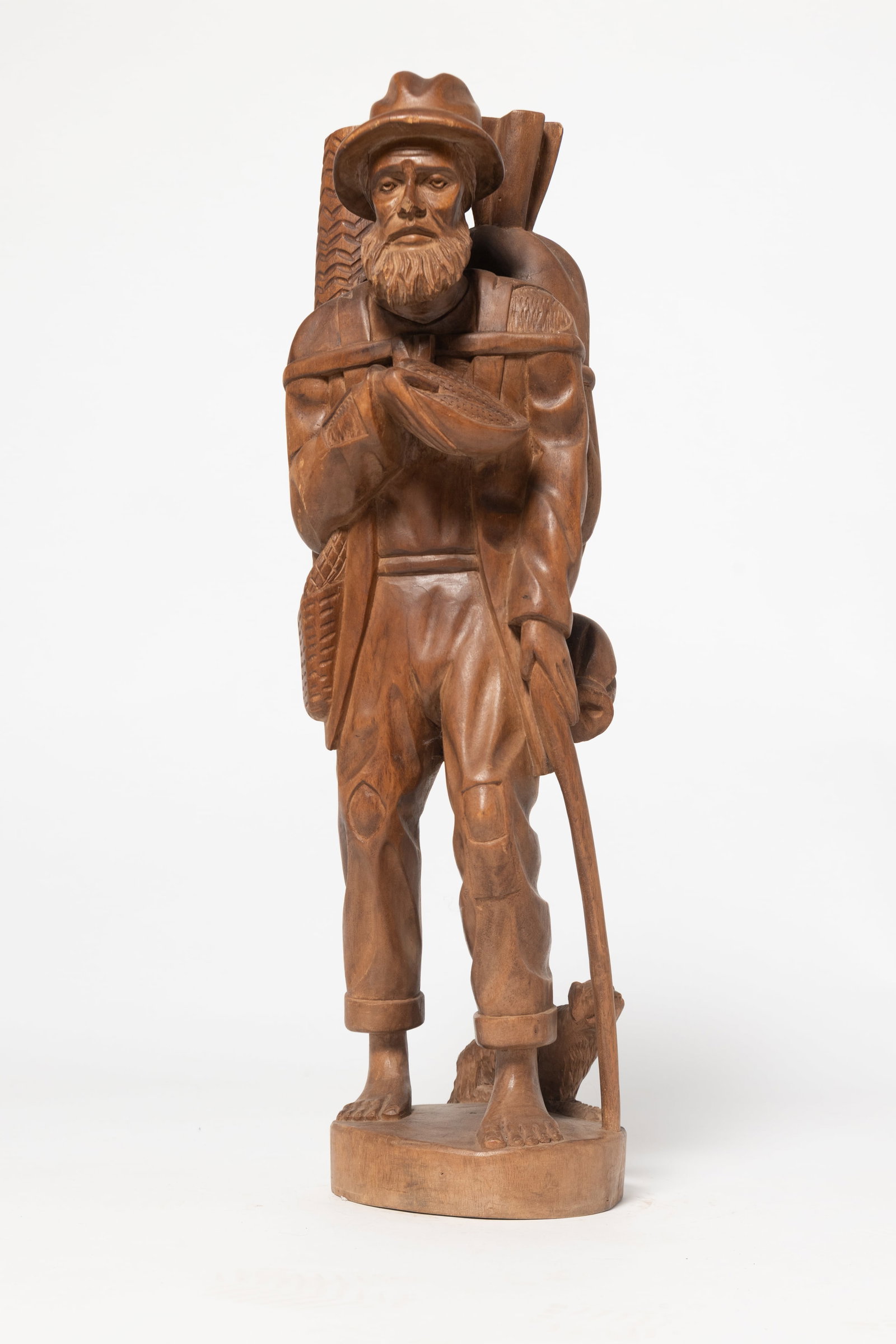 A TRAVELING MAN FOLKSY CARVING.: A TRAVELING MAN FOLKSY CARVING. American, 20th Century. Hardwood. Bearded man with walking stick, barefoot and hatted, carrying his bedroll, sack of belongings, with a bowl of what appears to be ears 