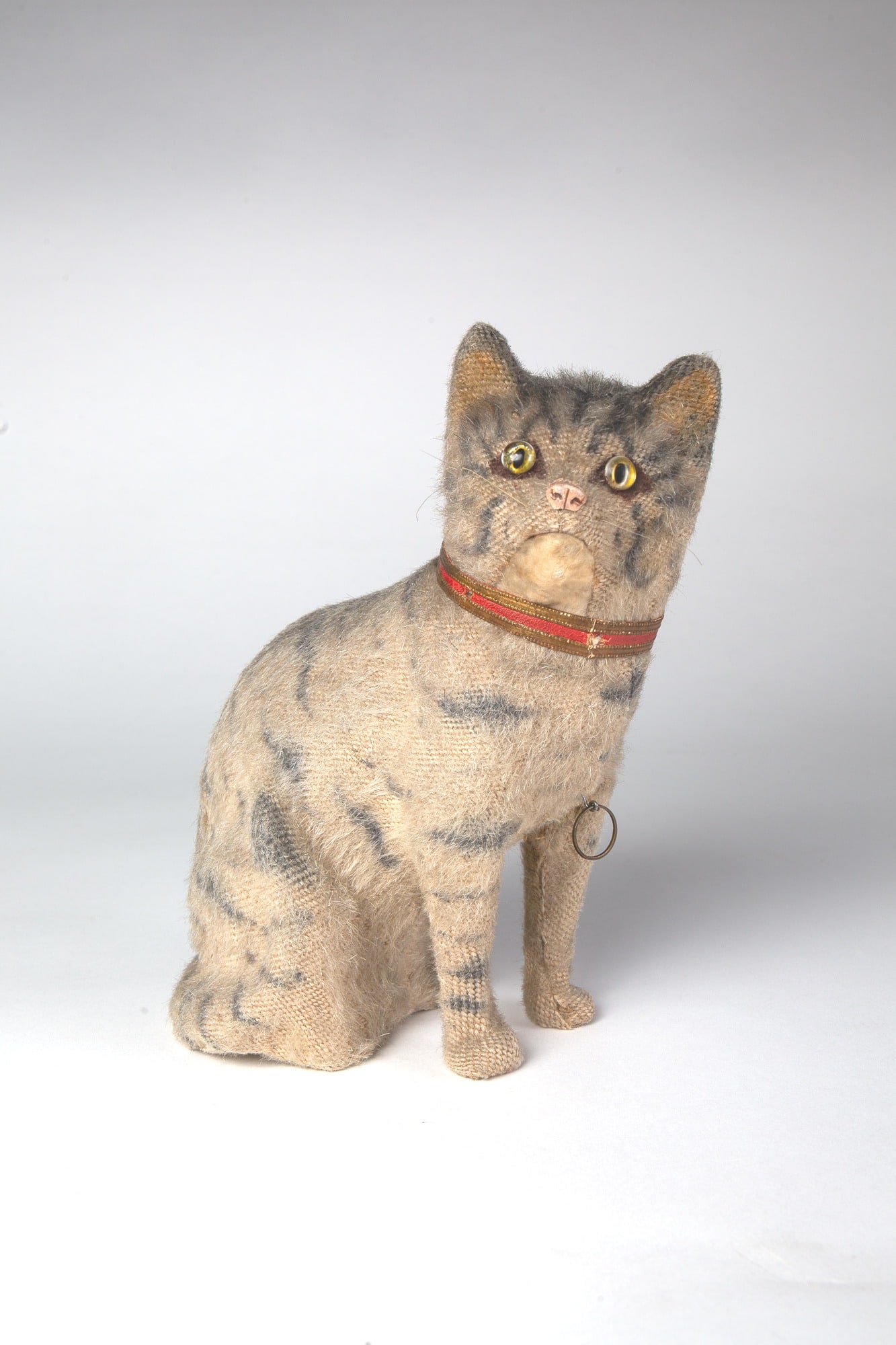 GREY-STRIPED MEOWING CAT TOY.: GREY-STRIPED MEOWING CAT TOY. Germany, late 19th or early 20th Century. Having a mohair body with glass eyes, Dresden collar, and whiskers; emits "meow" sound; 9"h. 4.5"w. Provenance: Nancy Goff (Alli