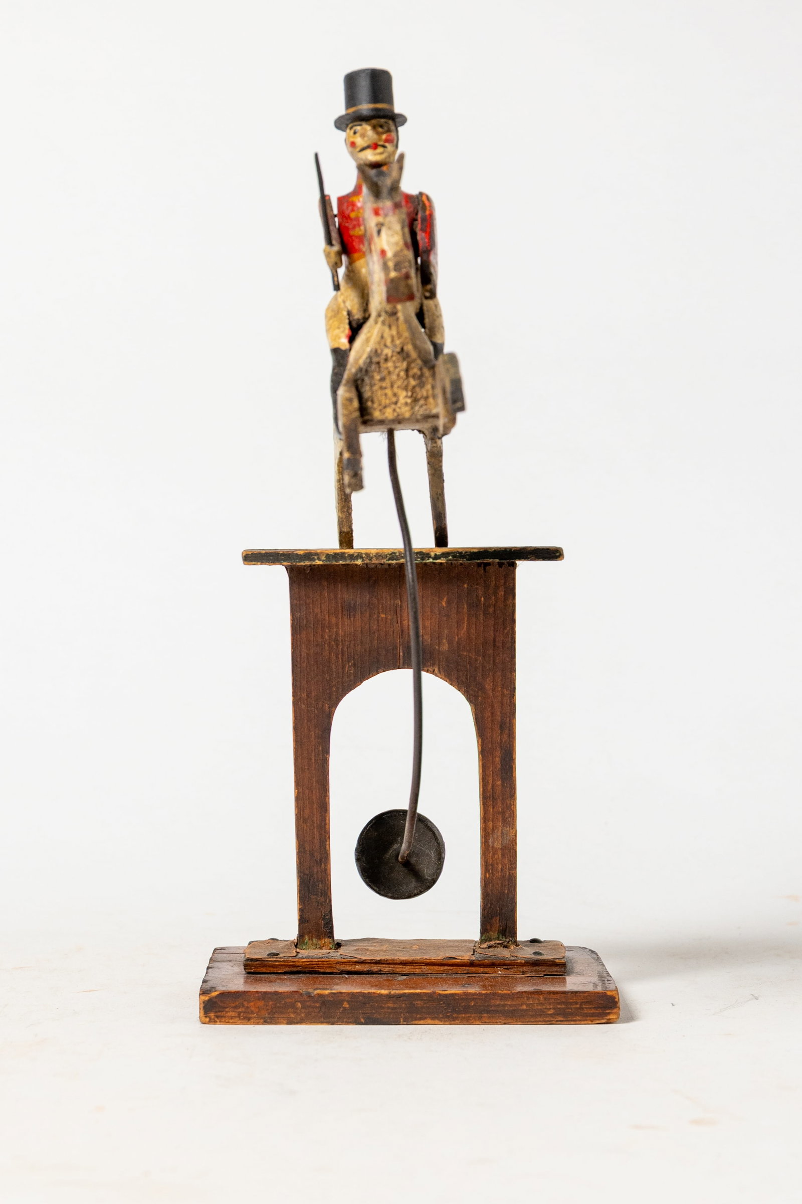 BALANCING HORSE AND RIDER TOY IN ORIGINAL PAINT.: BALANCING HORSE AND RIDER TOY IN ORIGINAL PAINT. American, 19th Century. A carved wood horse and rider wearing a top hat and a red coat with gold decoration, seated on a white horse with a red and gol