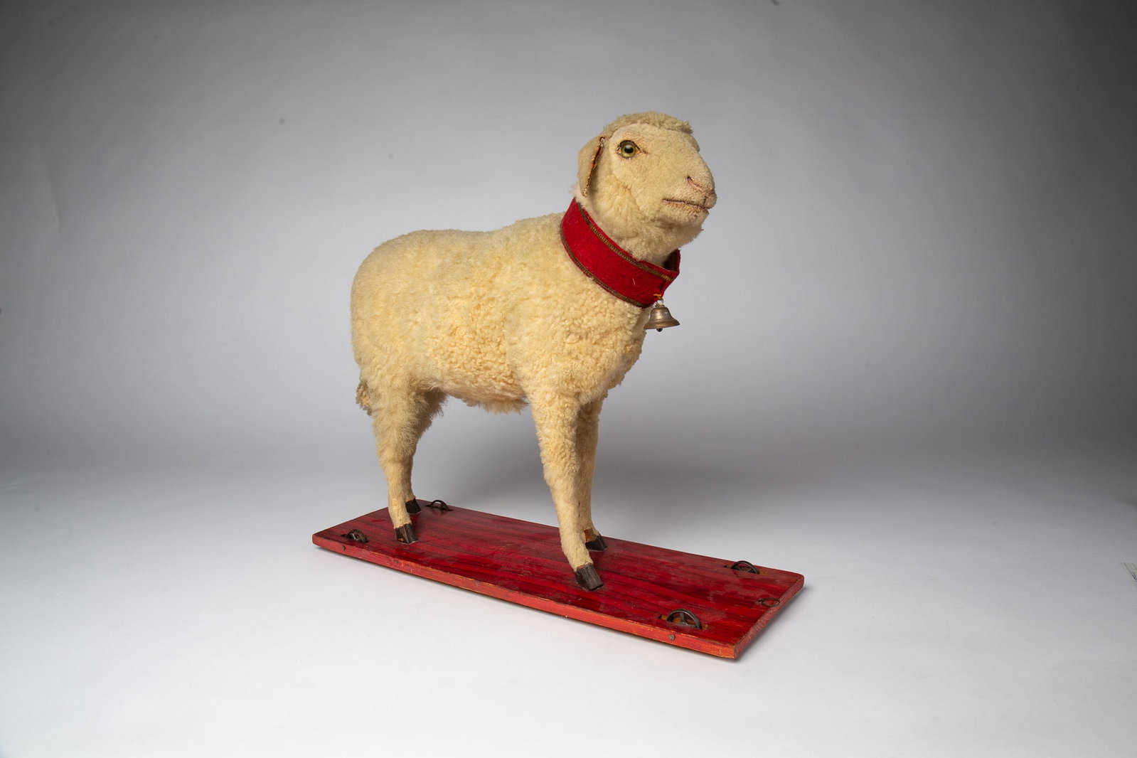 LARGE WOOLY LAMB PULL TOY WITH MOVEABLE HEAD.: LARGE WOOLY LAMB PULL TOY WITH MOVEABLE HEAD. Germany, late 19th or early 20th Century. Lamb with glass eyes and wood body covered by wool; having a red wool collar on neck with bell; red-painted wood