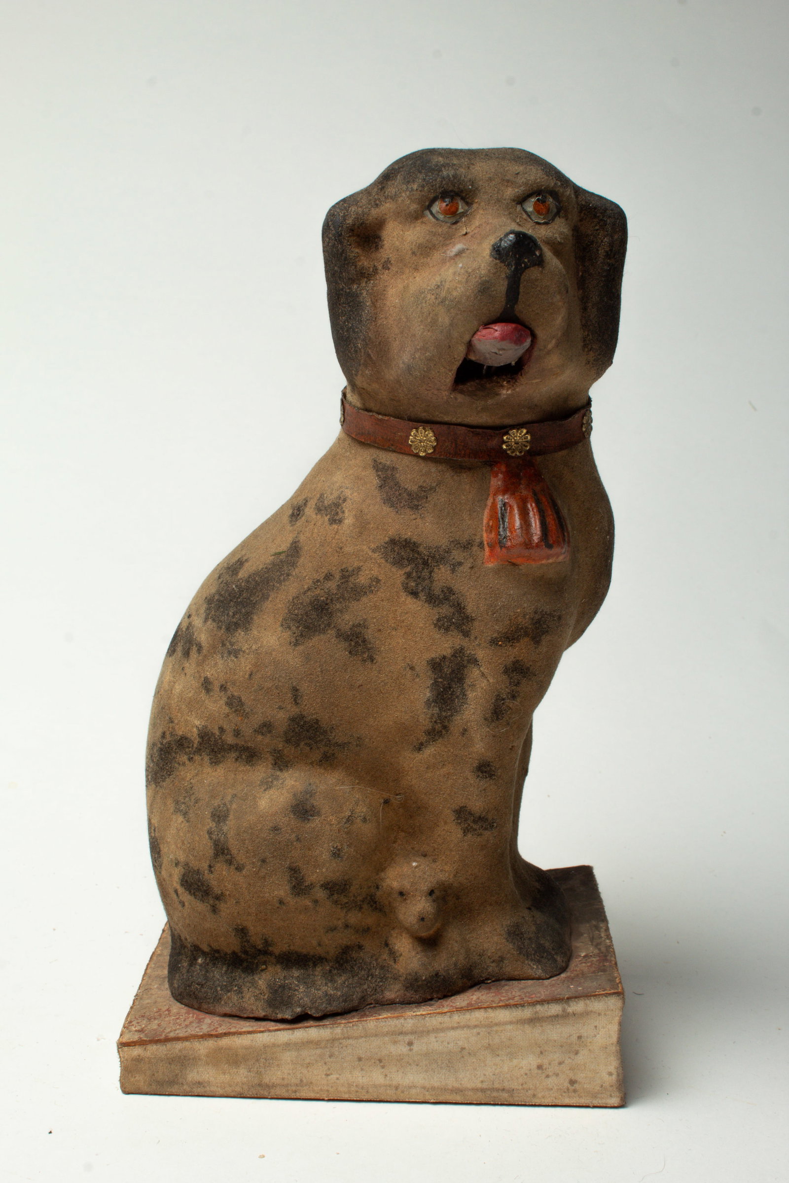 LARGE FULL BODIED DOG PIPSQUEAK.: LARGE FULL BODIED DOG PIPSQUEAK. Germany, early 20th Century. A seated puppy with a flocked mottled surface with a red collar with flowers and a tassel, and sticks its tongue out with pressed. Piece o