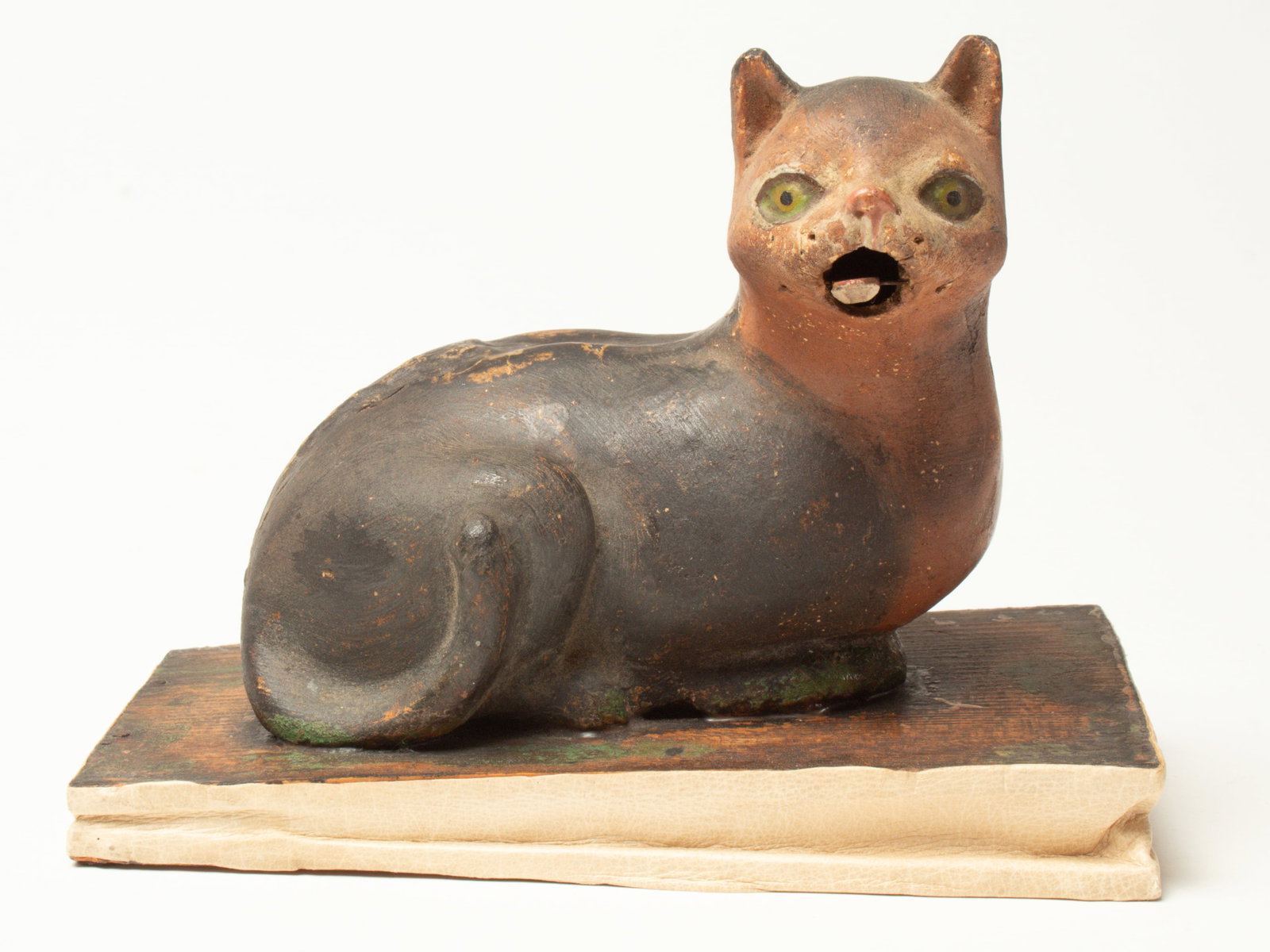 RECUMBENT CAT PIPSQUEAK.: RECUMBENT CAT PIPSQUEAK. Germany, early 20th Century. A brown and black composition cat with an open mouth, lying on a mottled base. Bellows are silent, but the mouth opens when pressed. 6"h. 7"d.