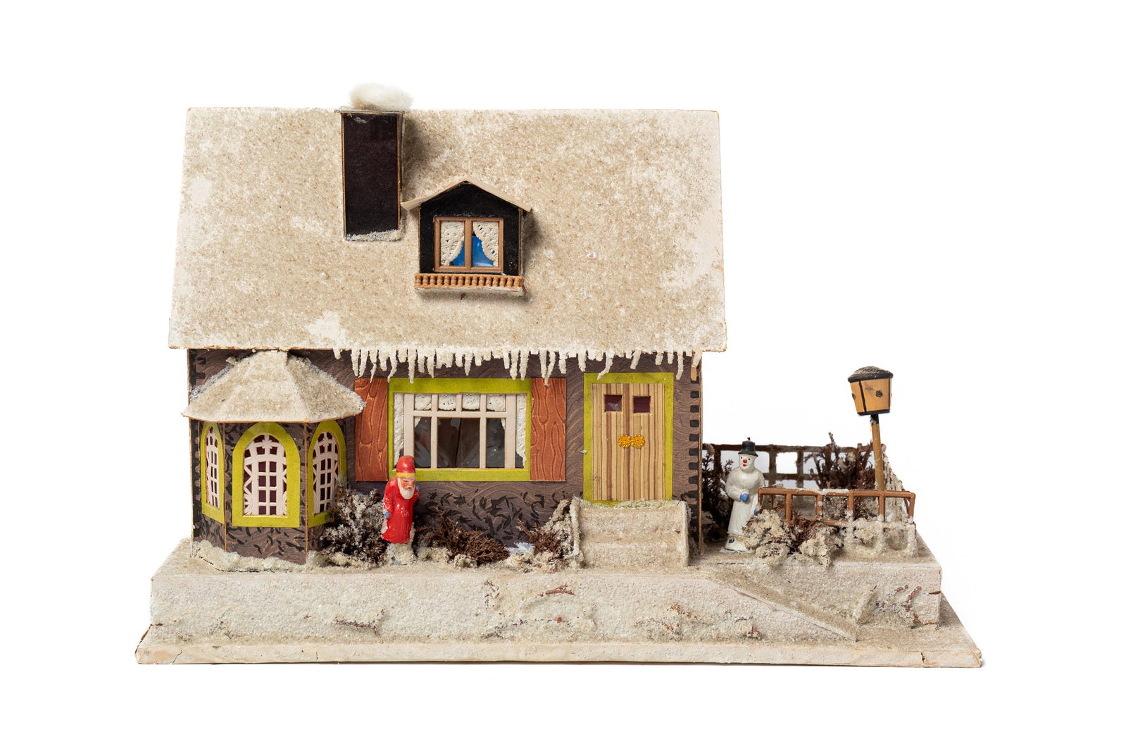 GERMAN PRESSED CARDBOARD DECORATED HOUSE.: GERMAN PRESSED CARDBOARD DECORATED HOUSE. Germany, early 20th Century. A house mounted on a board, mica-decorated roof, fenced-in side yard with a light post and snowman, bushes around the house with