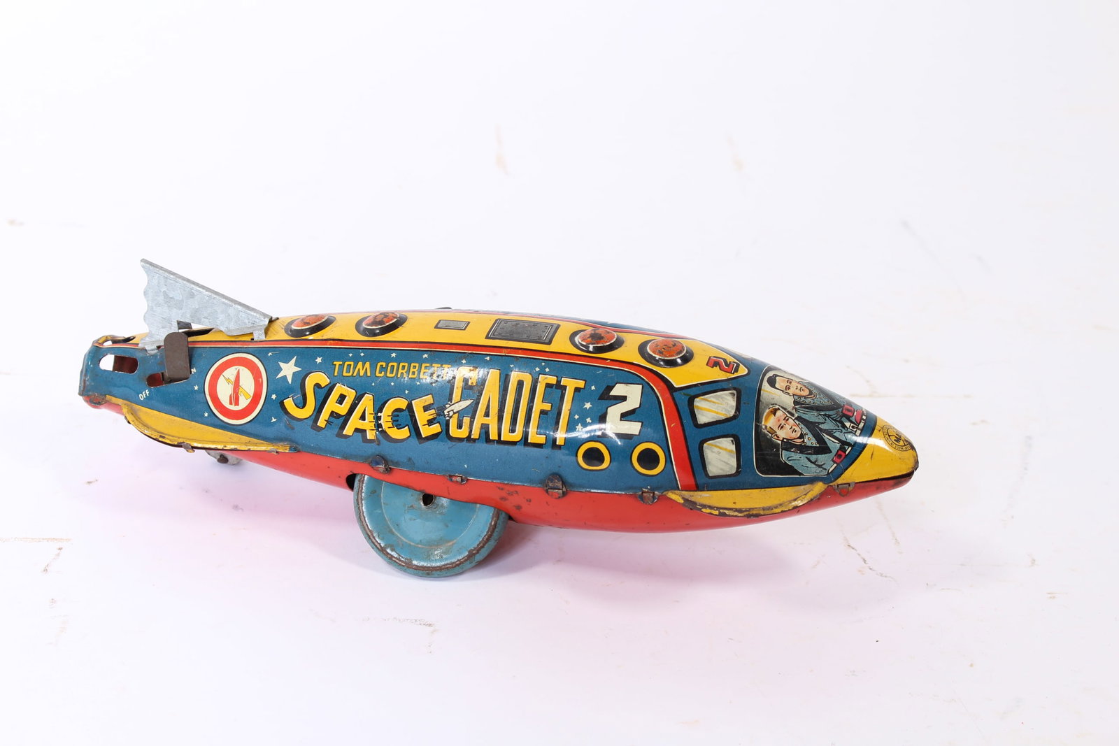 LOUIS MARX (NEW YORK, NEW YORK) TIN LITHO WINDUP TOM CORBETT SPARKLING SPACE SHIP.: LOUIS MARX (NEW YORK, NEW YORK) TIN LITHO WINDUP TOM CORBETT SPARKLING SPACE SHIP. American, 20th Century. Polychrome top reading "Tom Corbett Space Cadet," a red belly, and blue wheels, with a tin fi