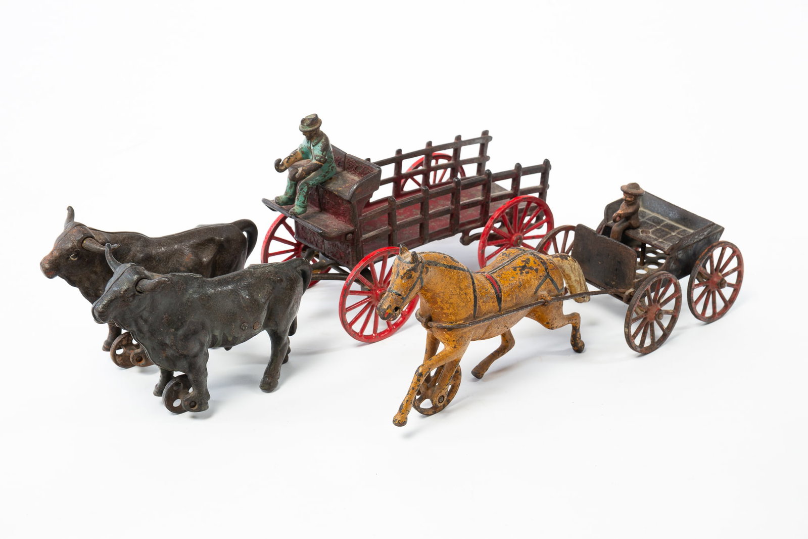 TWO PAINTED CAST IRON OXEN AND HORSE-DRAWN CARRIAGE TOYS.: TWO PAINTED CAST IRON OXEN AND HORSE-DRAWN CARRIAGE TOYS. American, late 19th or early 20th Century. One carriage drawn by two oxen while the other has a single horse in front. Both wagons with a seat