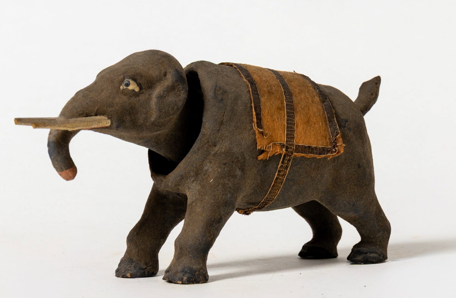COMPOSITION ELEPHANT NODDER.: COMPOSITION ELEPHANT NODDER. Germany, early 20th Century. A composition elephant with slightly fuzzy body, white and black painted eyes, pink end of trunk, white-painted wood tusks, and a felt saddle 