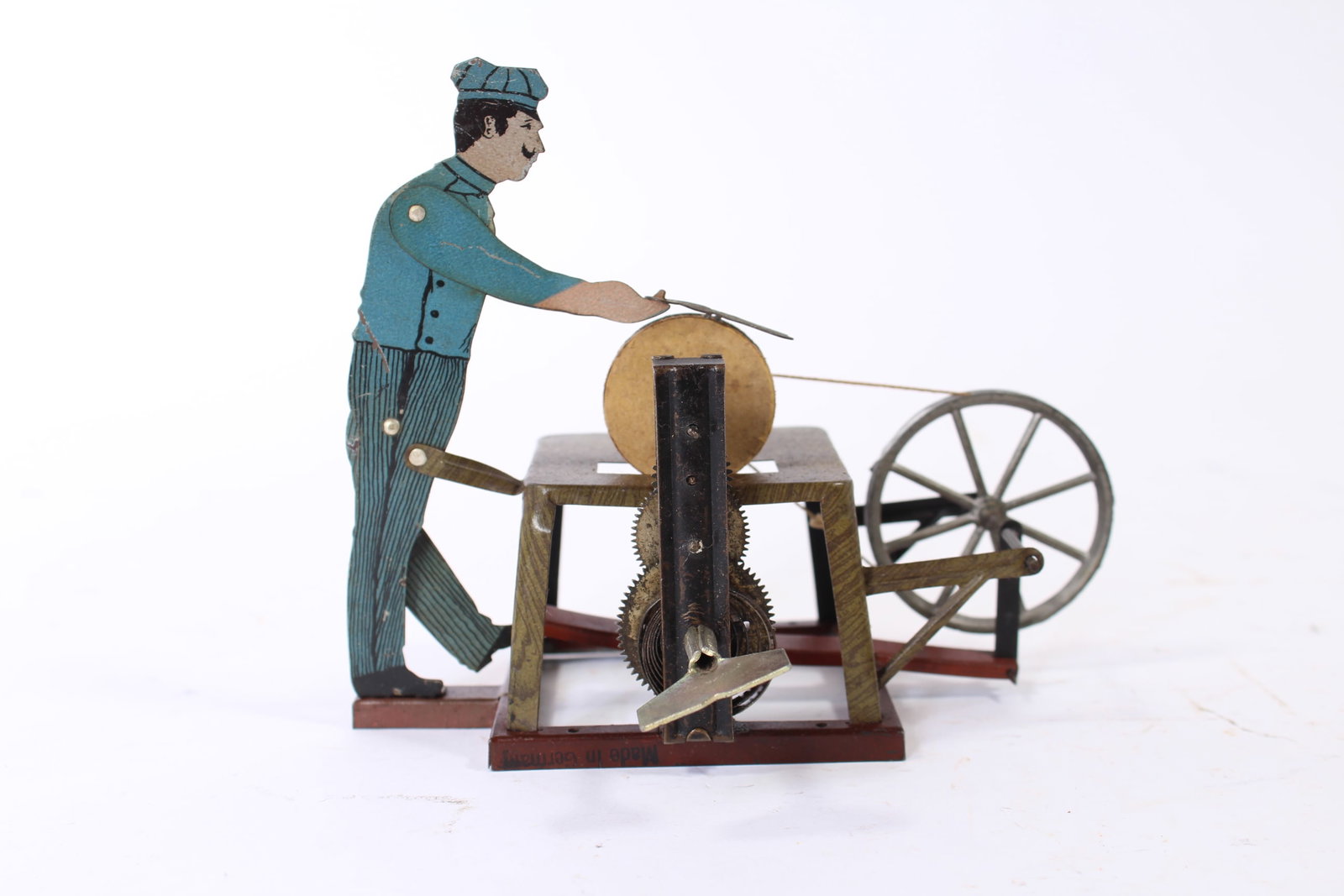 TIN LITHO WINDUP SCISSOR SHARPENING MAN.: TIN LITHO WINDUP SCISSOR SHARPENING MAN. German, 20th Century. Man sharpening a pair of scissors on a treadle wheel, a windup key on the side. 5.5"h. 5.25"w. 7"d. Provenance: From the Lifetime