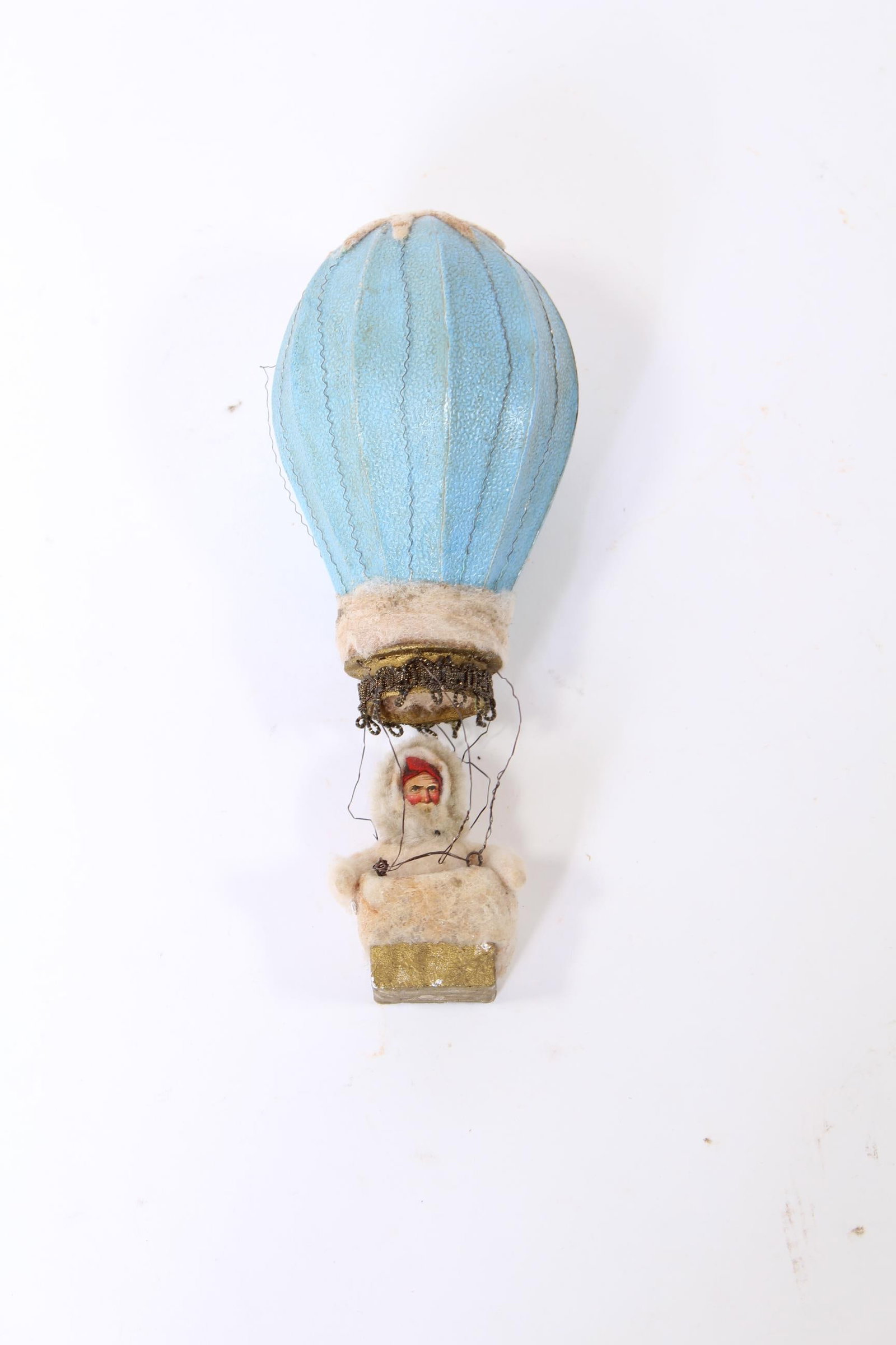 DRESDEN HOT AIR BALLOON ORNAMENT.: DRESDEN HOT AIR BALLOON ORNAMENT. Germany, early 20th Century. Oil cloth hot air balloon in blue, Santa sitting in the gondola in a fuzzy outfit. 8.5"h. Provenance: Nancy Goff (Alliance, Ohio).